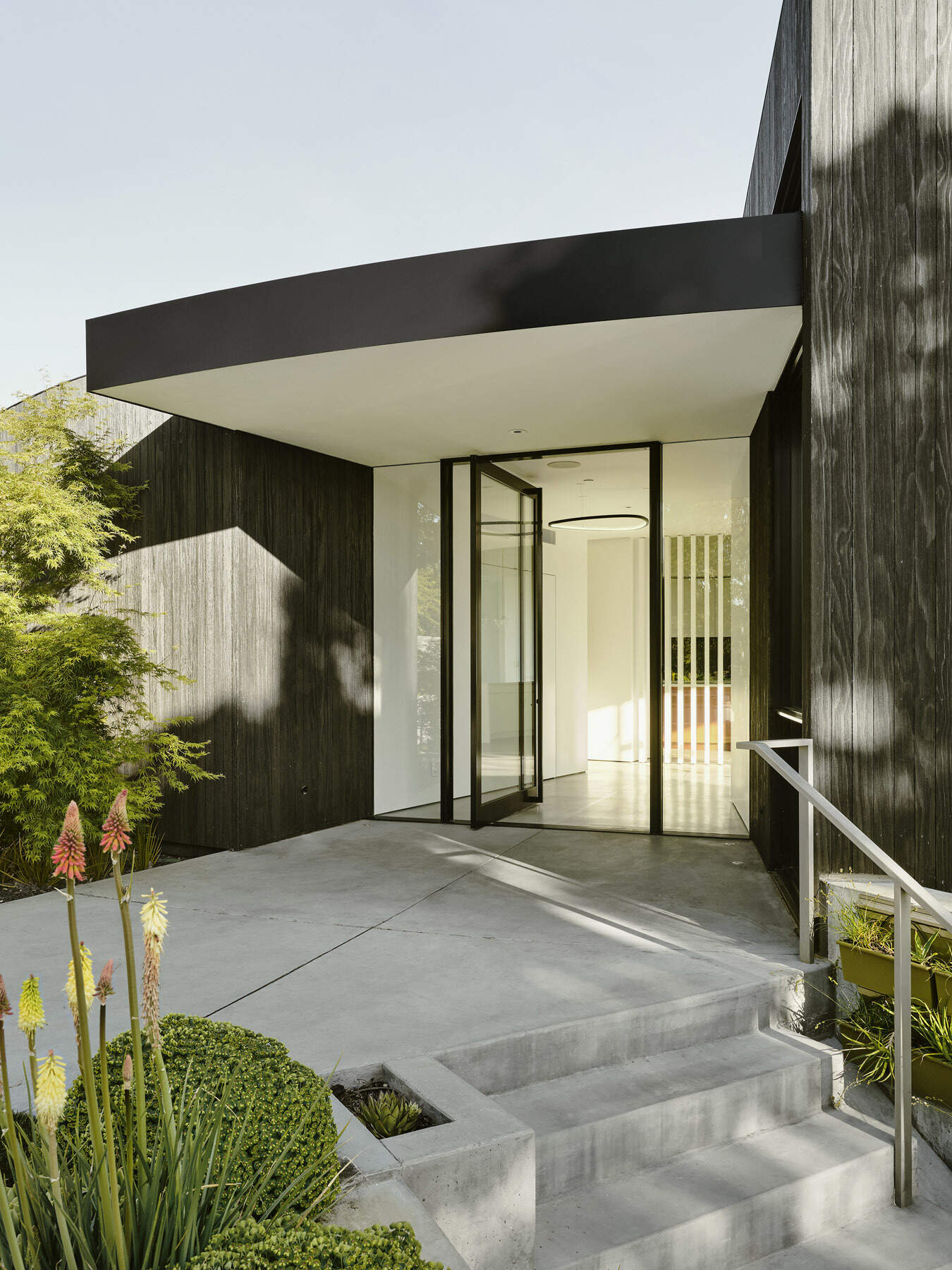 Charred wood siding, seamless concrete floors, and curved white walls modernize the Round House while respecting its original 1960s geometry.