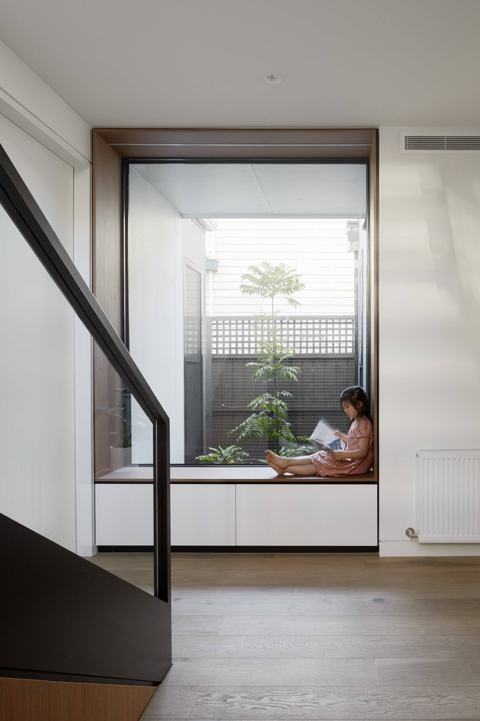 Steel stairs lead to the second floor, while a built in wood lined window seat at their base offers a quiet view to a side garden.