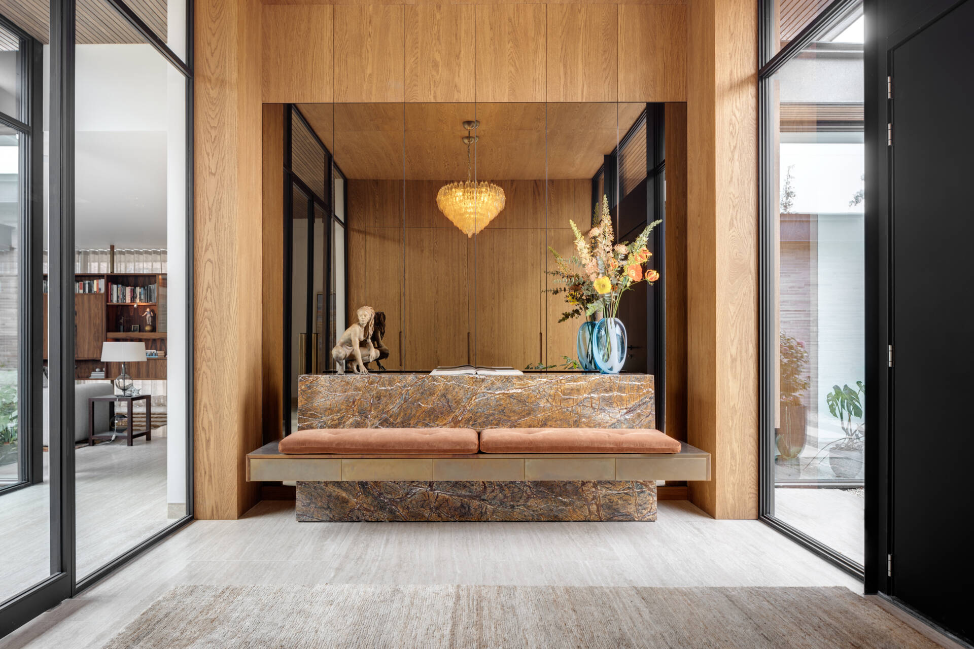 The entrance occupies the intermediate volume between the two wings. It frames a direct view into the patio, immediately establishing the courtyard as the focal point of the home.