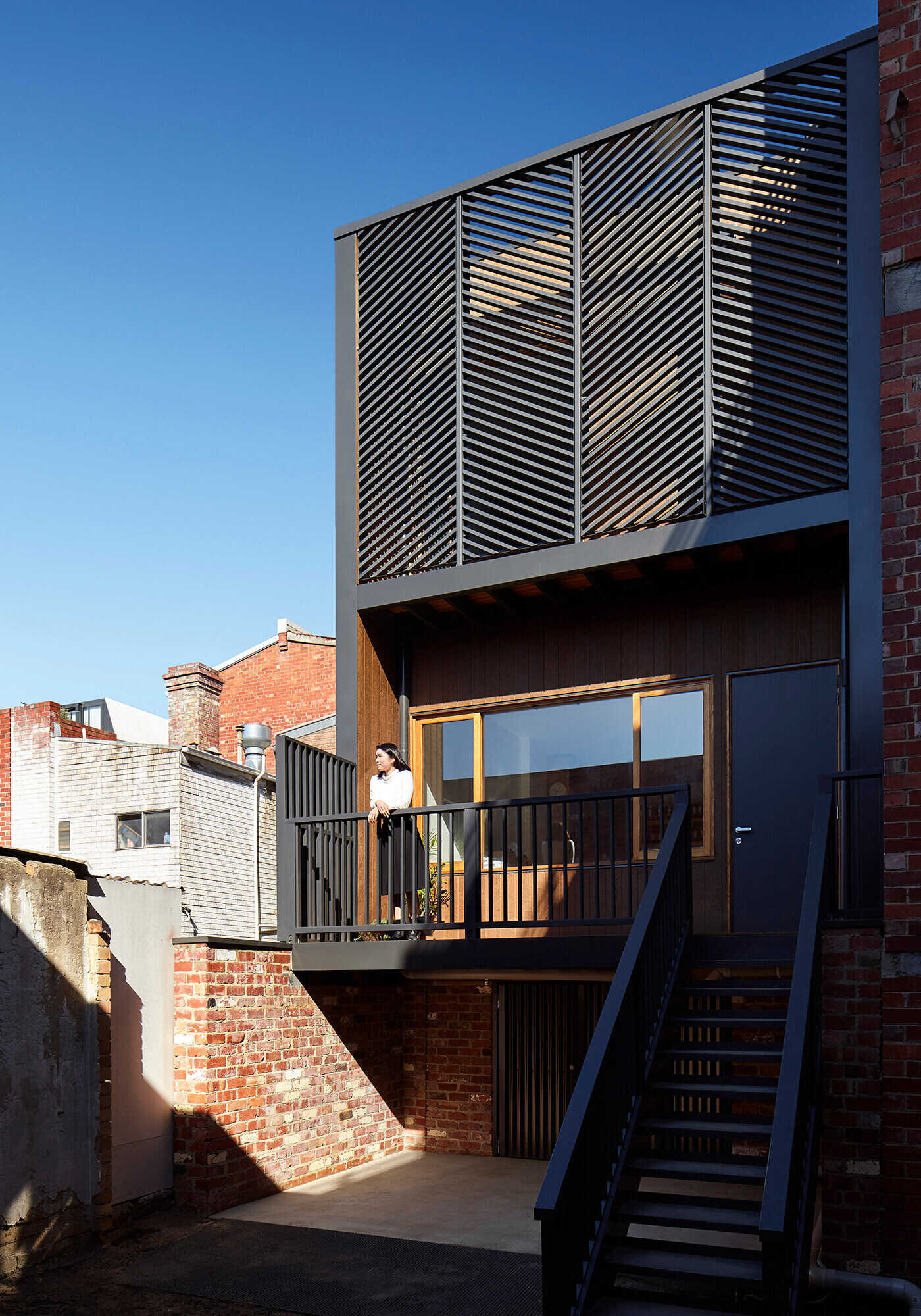 The heritage facade remains intact, but diagonal black screens and laneway steps hint at the modern renovation within.