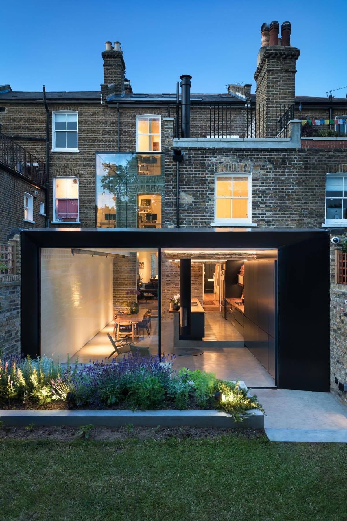 A dramatic double height frameless glass extension transforms a traditional London Victorian home into a light filled contemporary space.