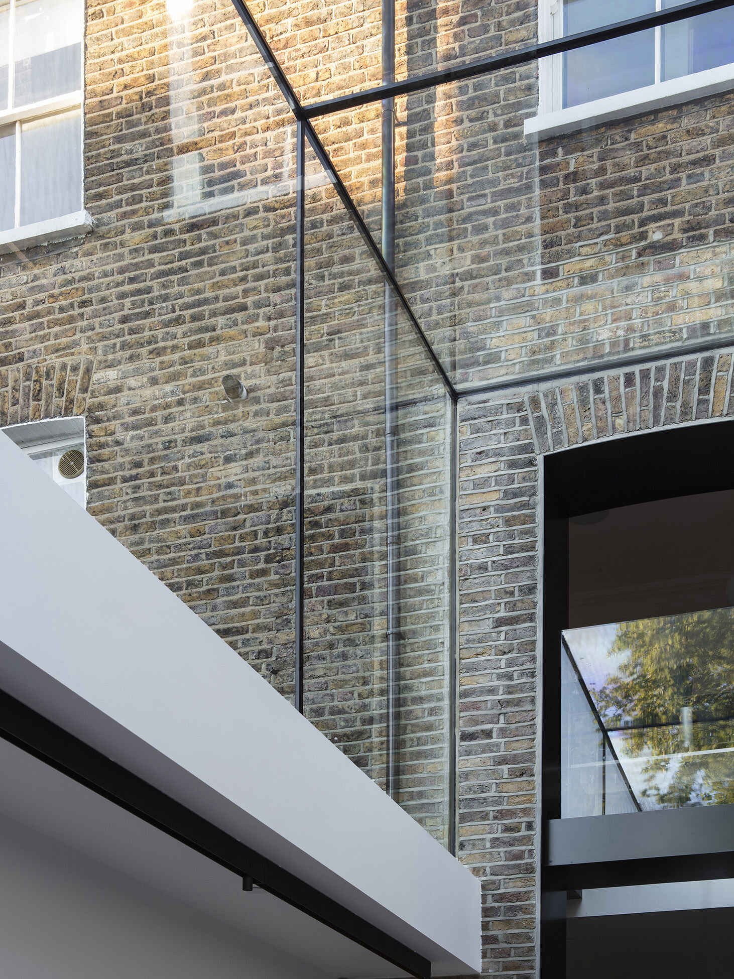 A dramatic double height frameless glass extension transforms a traditional London Victorian home into a light filled contemporary space.