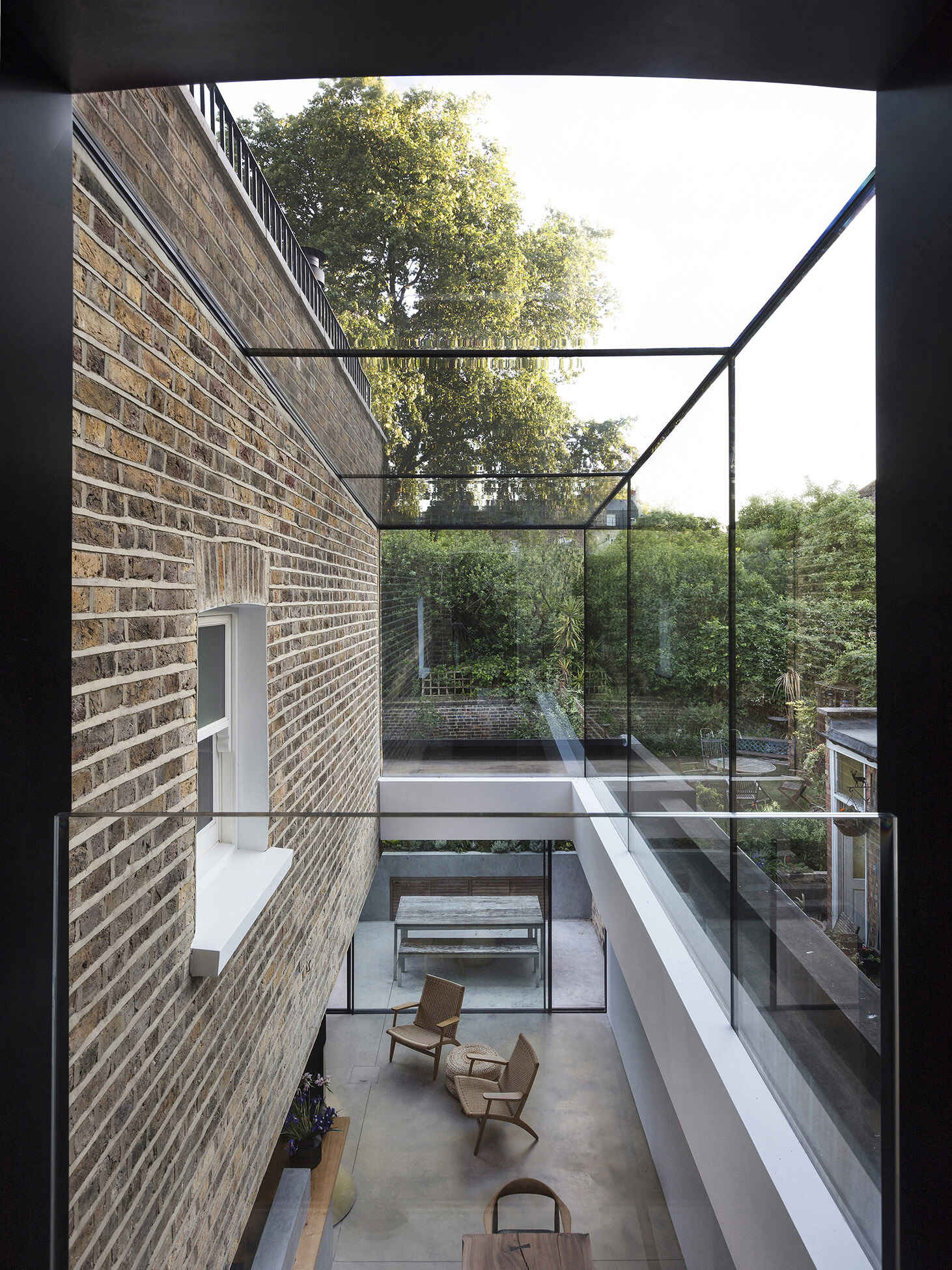 A dramatic double height frameless glass extension transforms a traditional London Victorian home into a light filled contemporary space.