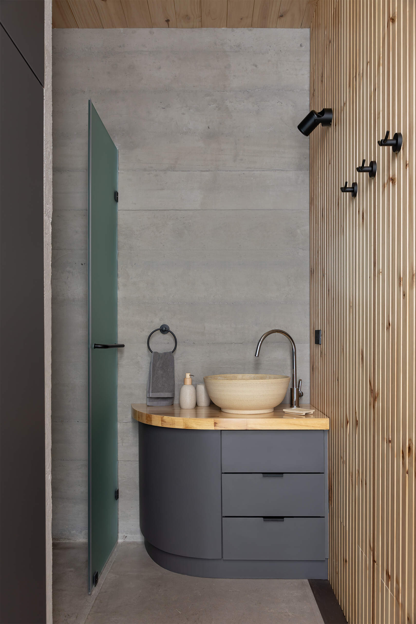 Wet areas are compact and integrated into the structural rhythm, with custom built-in elements crafted on site.