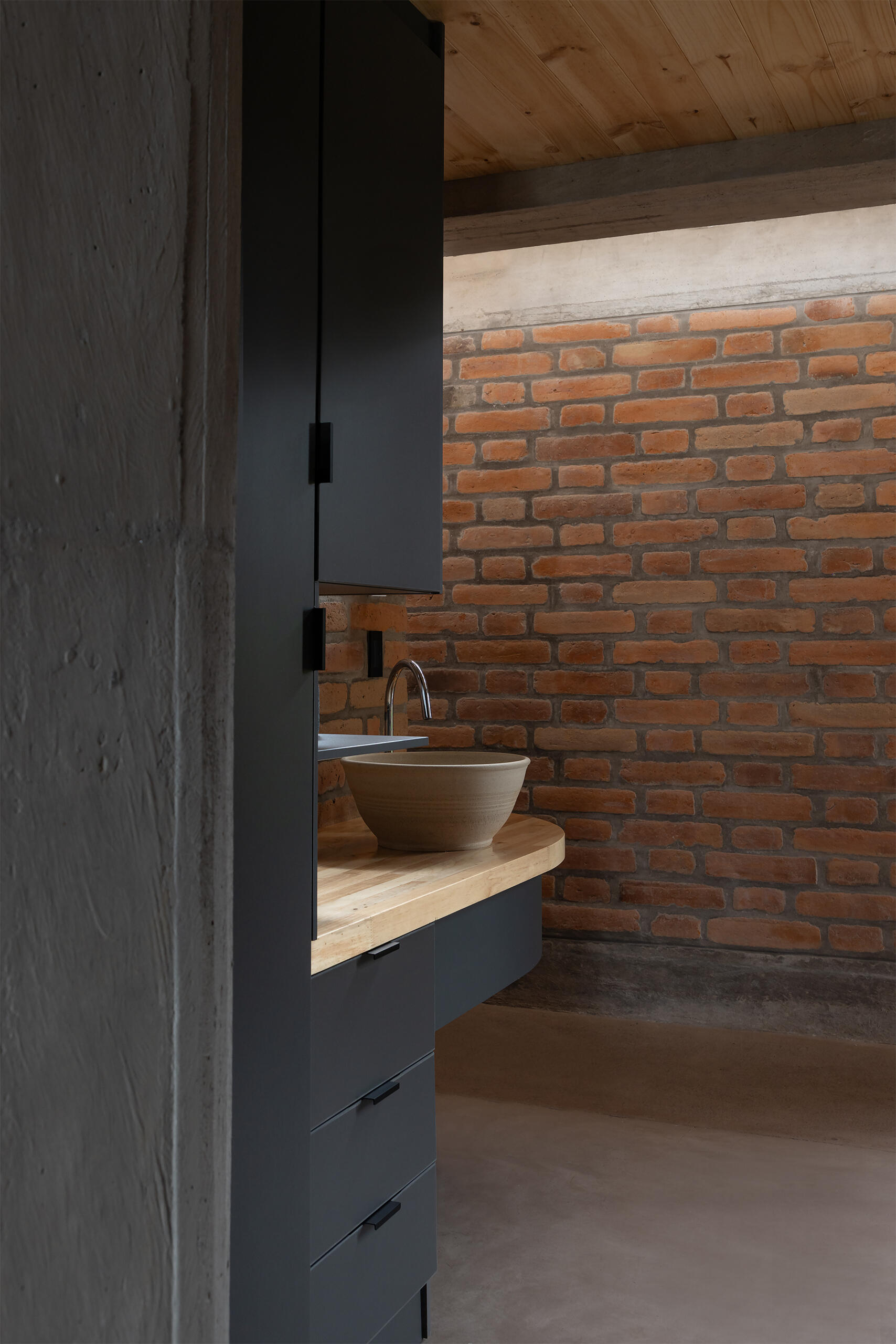 Wet areas are compact and integrated into the structural rhythm, with custom built-in elements crafted on site.