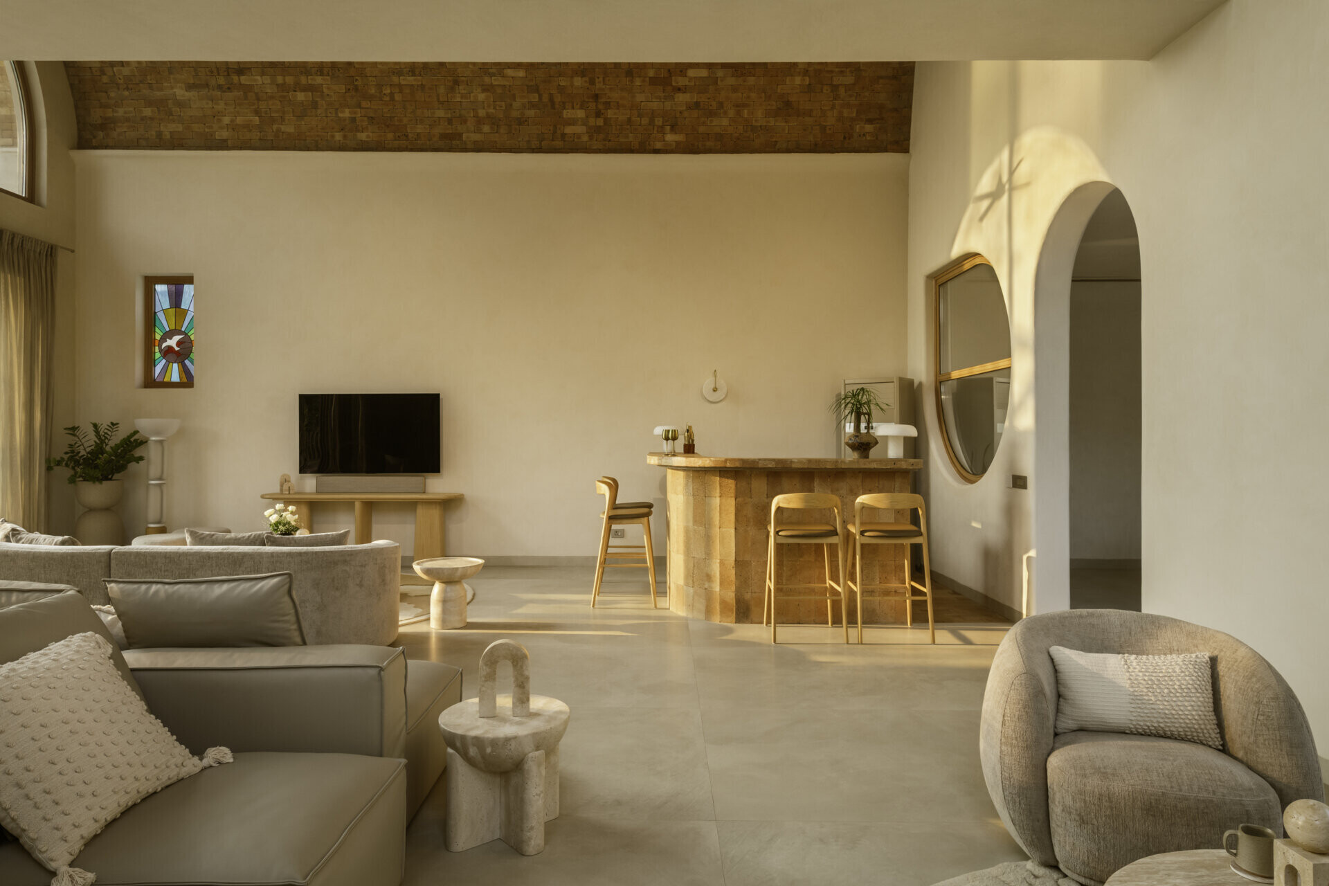 A circular window and brick-built bar blend into the vaulted architecture, creating a sculptural focal point within the monochrome interior of House of Tao.