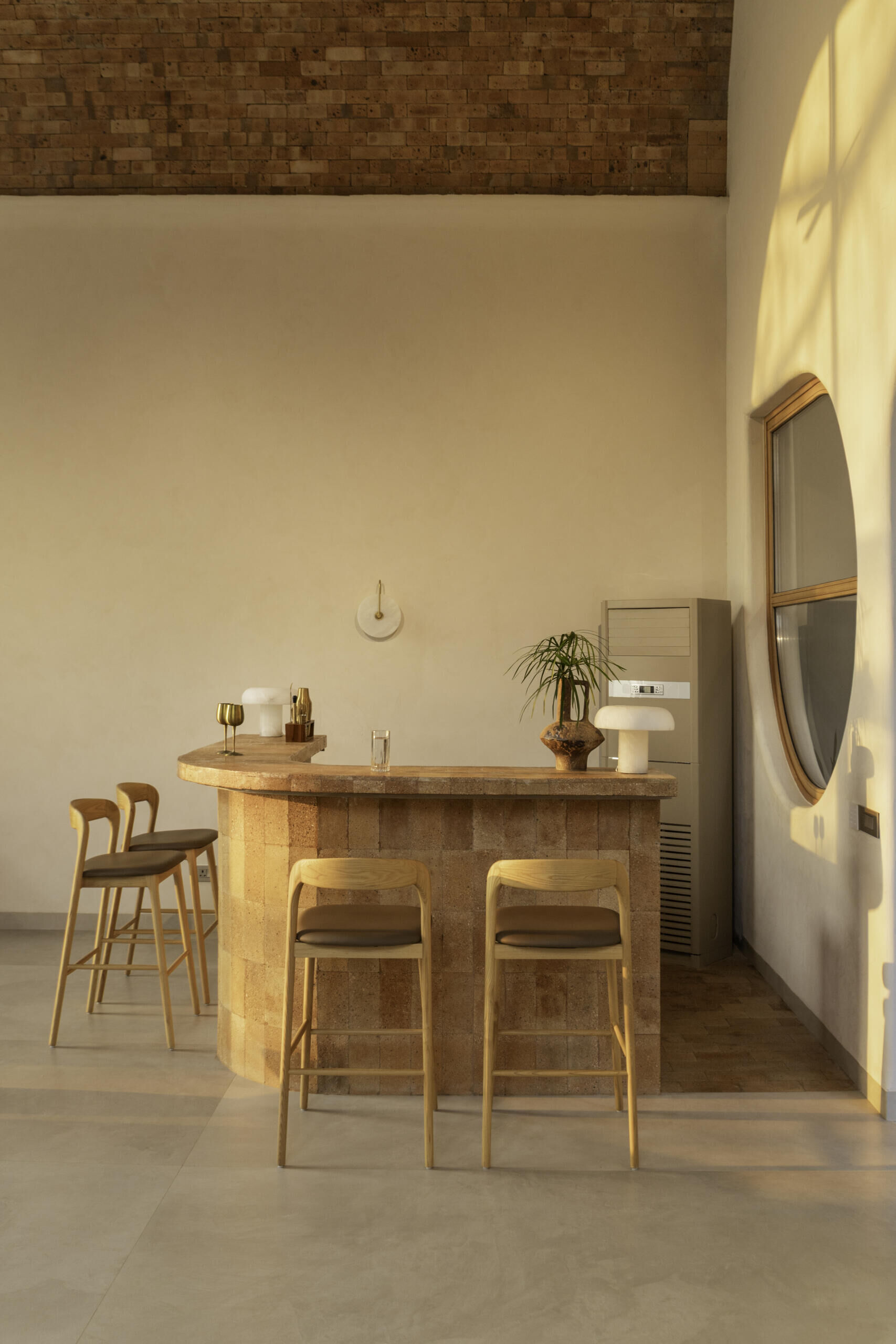 A circular window and brick-built bar blend into the vaulted architecture, creating a sculptural focal point within the monochrome interior of House of Tao.
