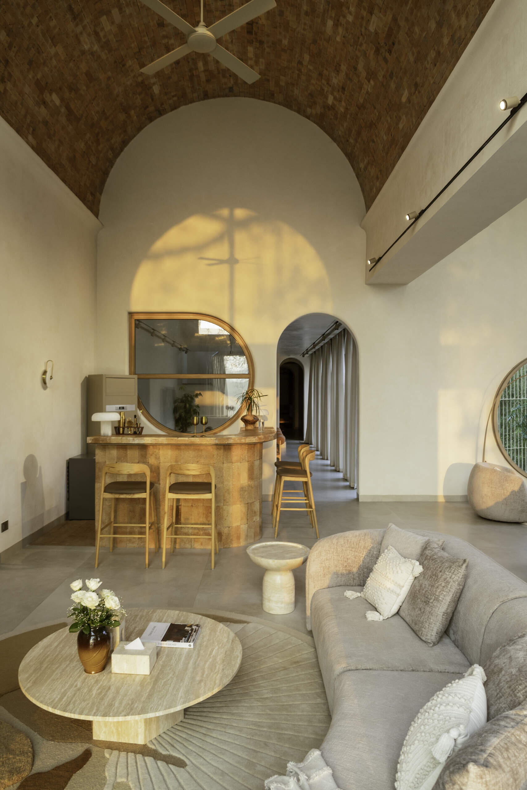A circular window and brick-built bar blend into the vaulted architecture, creating a sculptural focal point within the monochrome interior of House of Tao.