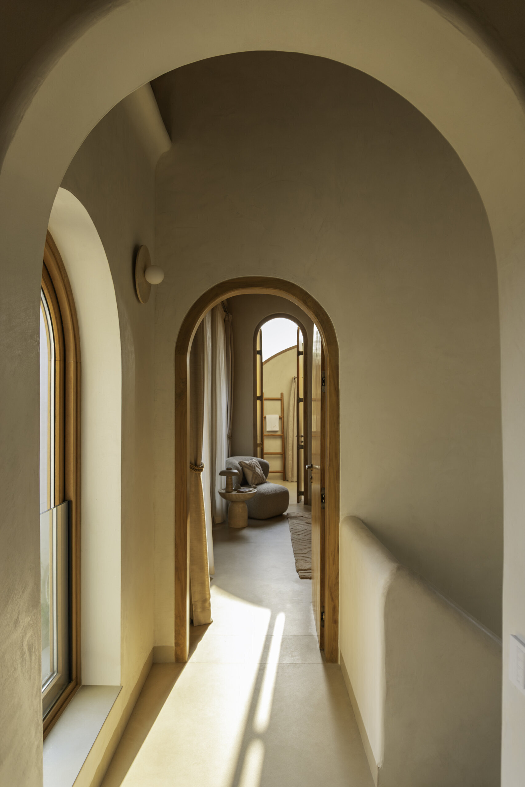 Curved openings and consistent lime plaster finishes guide movement through the home, maintaining visual calm between public and private spaces.
