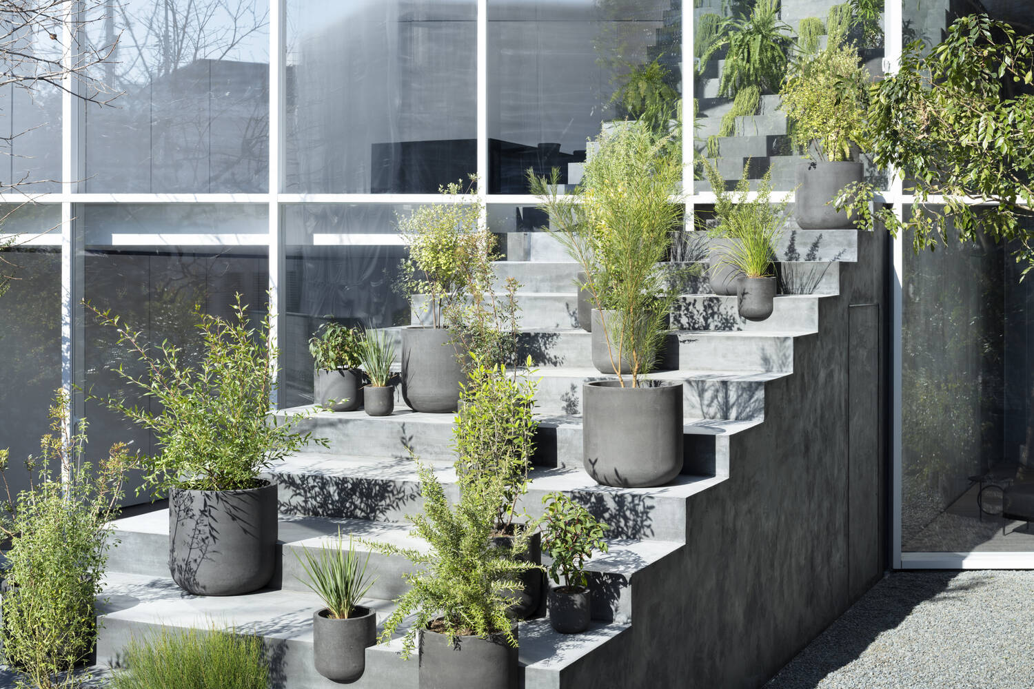 A minimalist Tokyo home where a single staircase starts in the garden, continues indoors, and rises toward a skylight, turning everyday movement into the home’s most striking architectural feature.