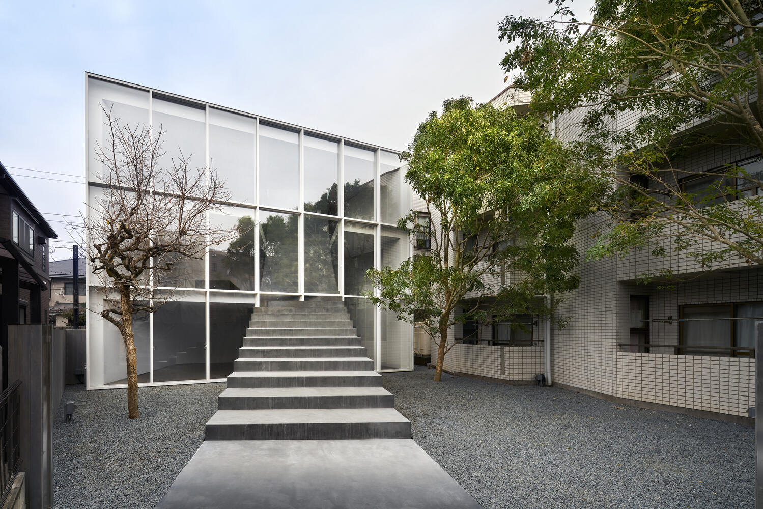 A minimalist Tokyo home where a single staircase starts in the garden, continues indoors, and rises toward a skylight, turning everyday movement into the home’s most striking architectural feature.