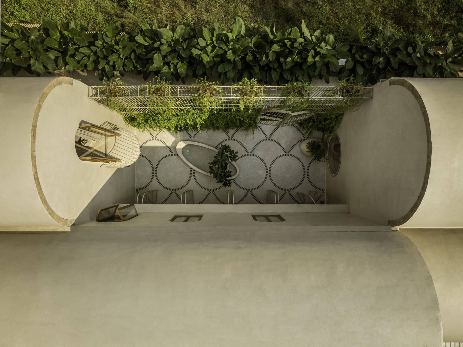 At the heart of the house, a courtyard with green marble terrazzo flooring and an elliptical sit-out wraps around a tree, reinterpreting traditional Goan balcão seating.