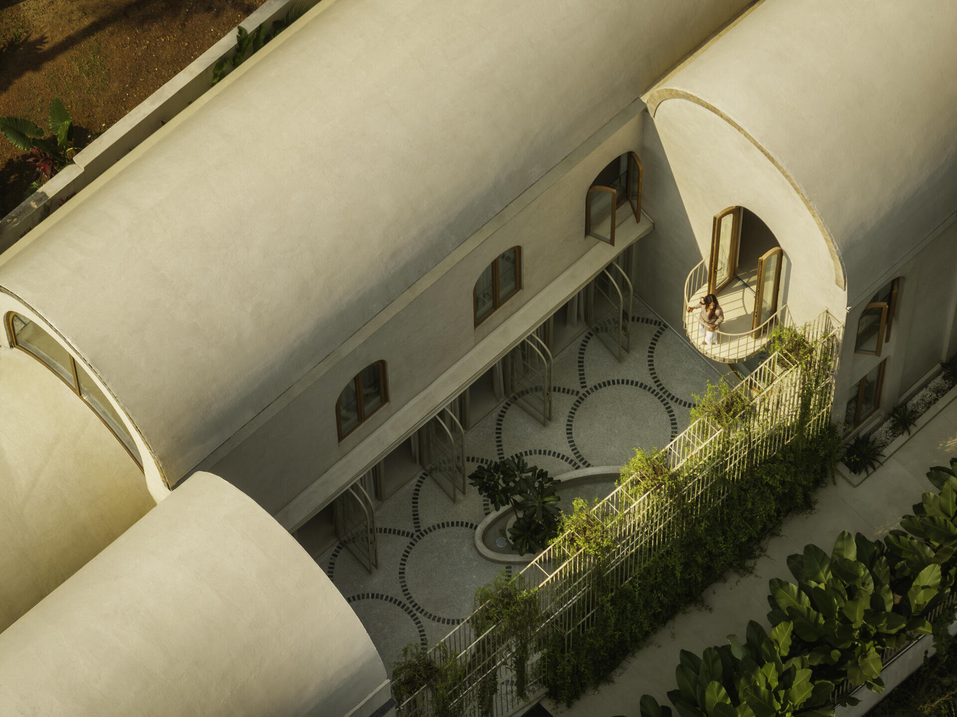 At the heart of the house, a courtyard with green marble terrazzo flooring and an elliptical sit-out wraps around a tree, reinterpreting traditional Goan balcão seating.