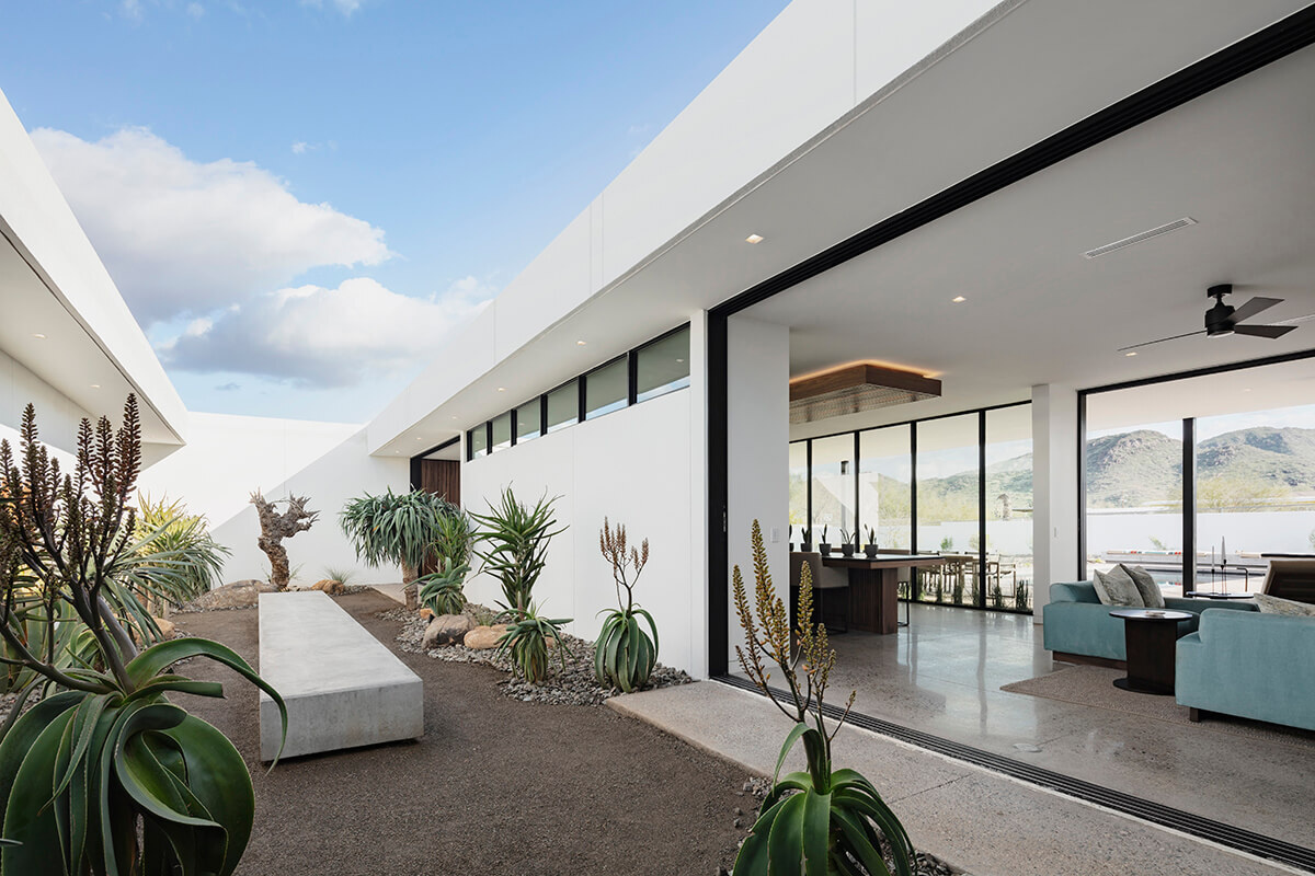 A private courtyard filled with sculptural desert plants becomes the focal point of this Arizona retreat. Pocketing glass doors connect the living room to a shaded outdoor bench and garden views.