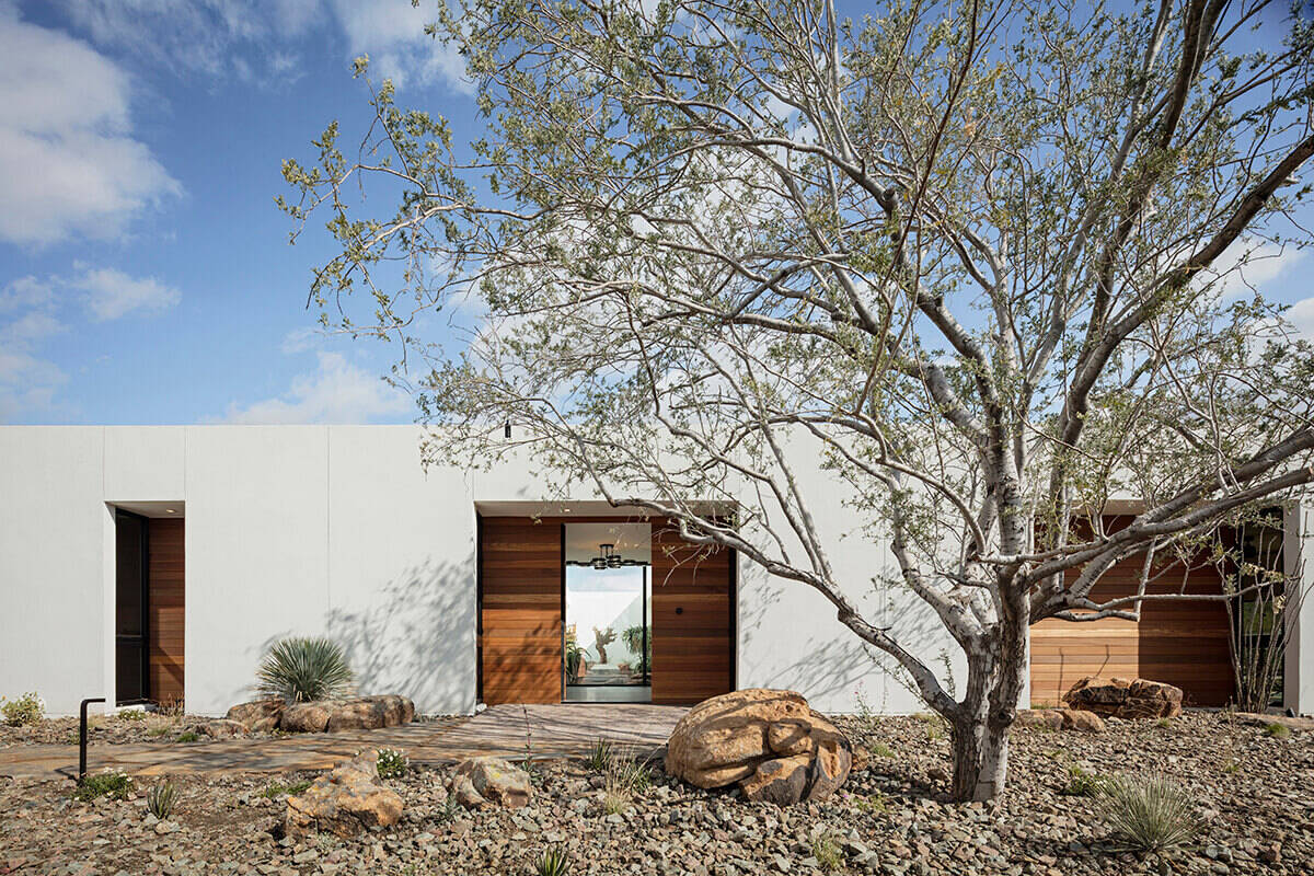 This modern desert home in Phoenix uses white stucco, Ipe wood niches, and a rattlesnake fence to create privacy while staying low and modern. The “O” shaped layout hides a serene courtyard at its heart.