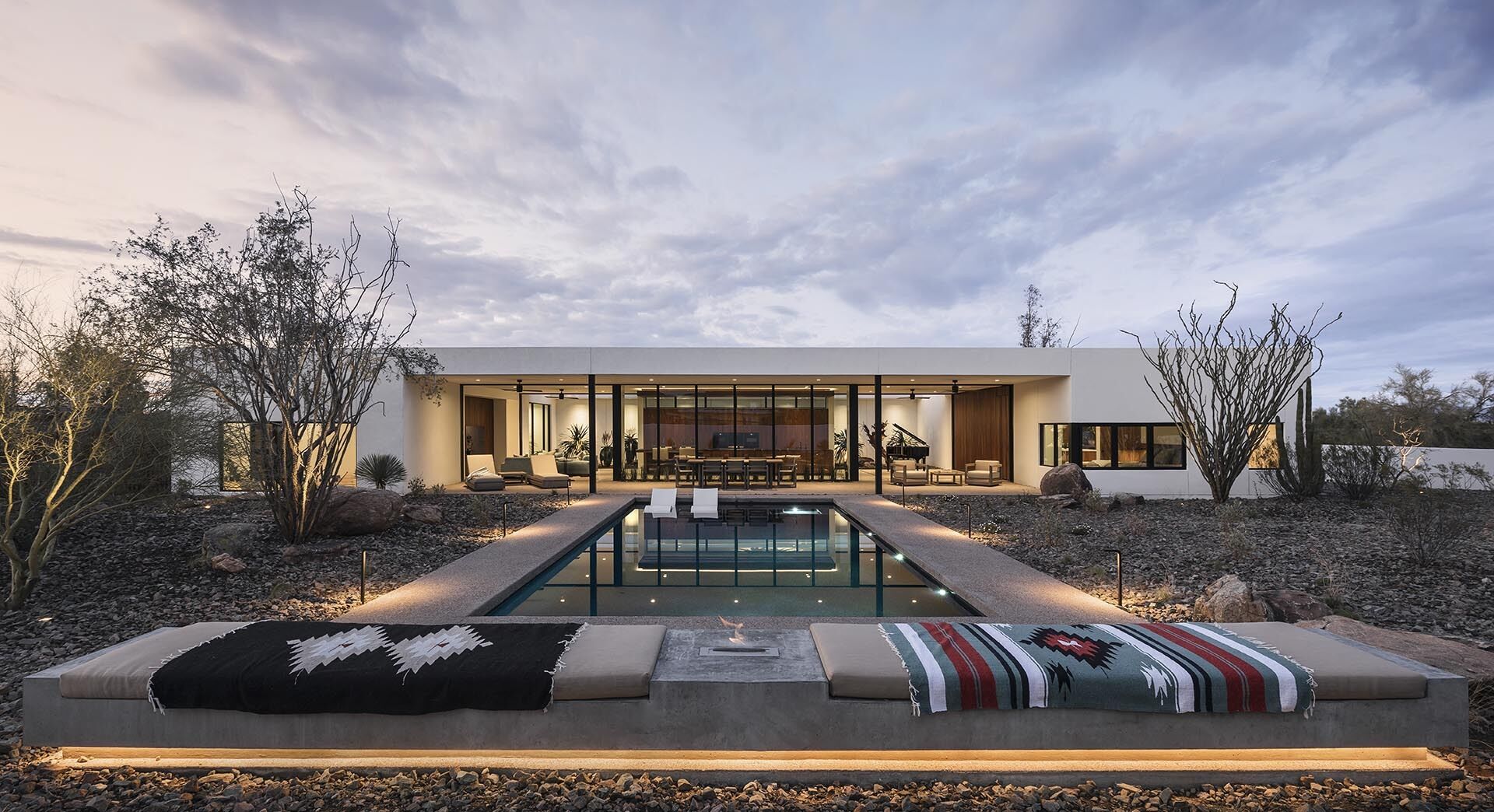 This modern desert home in Phoenix uses white stucco, Ipe wood niches, and a rattlesnake fence to create privacy while staying low and modern. The “O” shaped layout hides a serene courtyard at its heart.