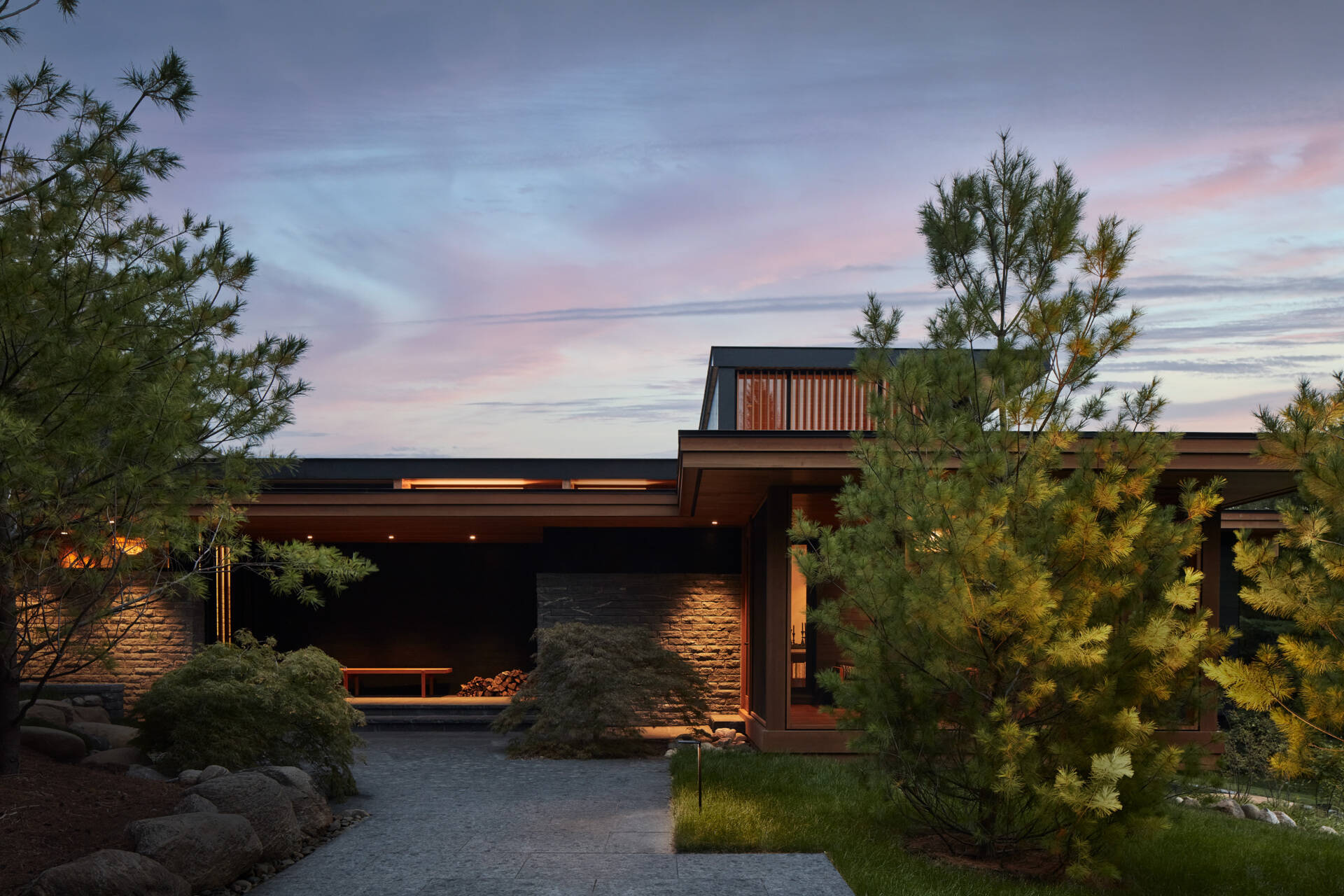 Muros bajos apilados de granito local organizan la residencia y hacen referencia a los tradicionales bordes de piedra del campo. El revestimiento de fresno termomodificado, la madera de origen local, el hormigón, la piedra y los detalles en metal negro crean una apariencia fuerte y duradera.