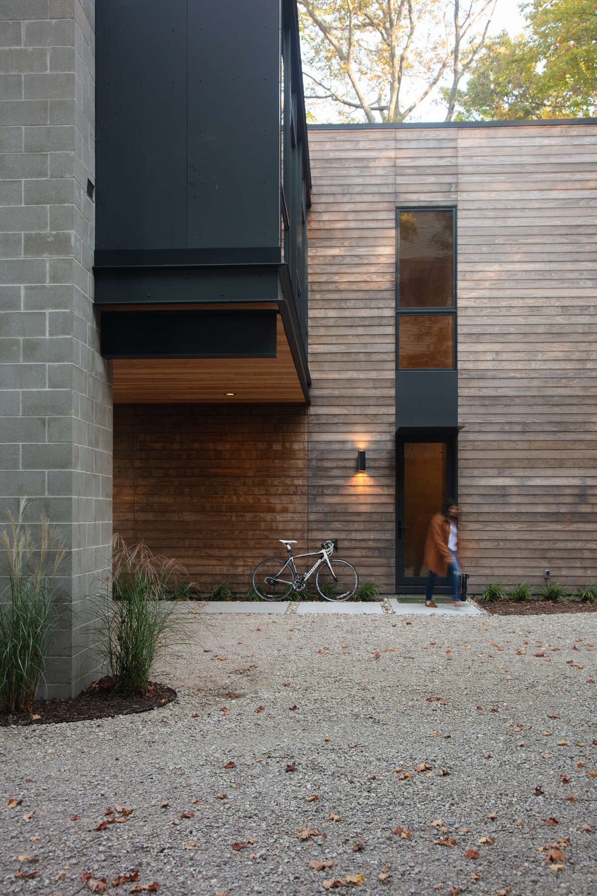 The exterior of this modern home combines unfinished Kebony wood, glass, and painted metal panel.