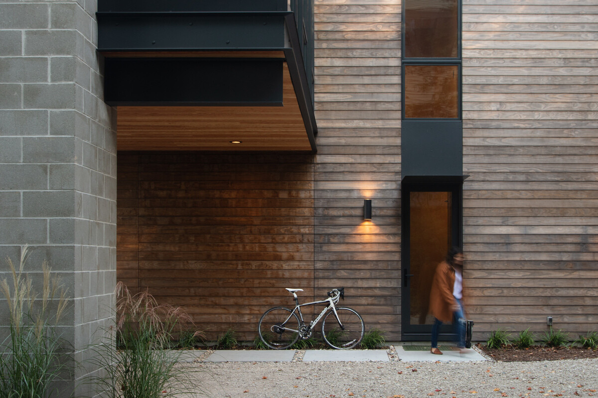 The exterior of this modern home combines unfinished Kebony wood, glass, and painted metal panel.