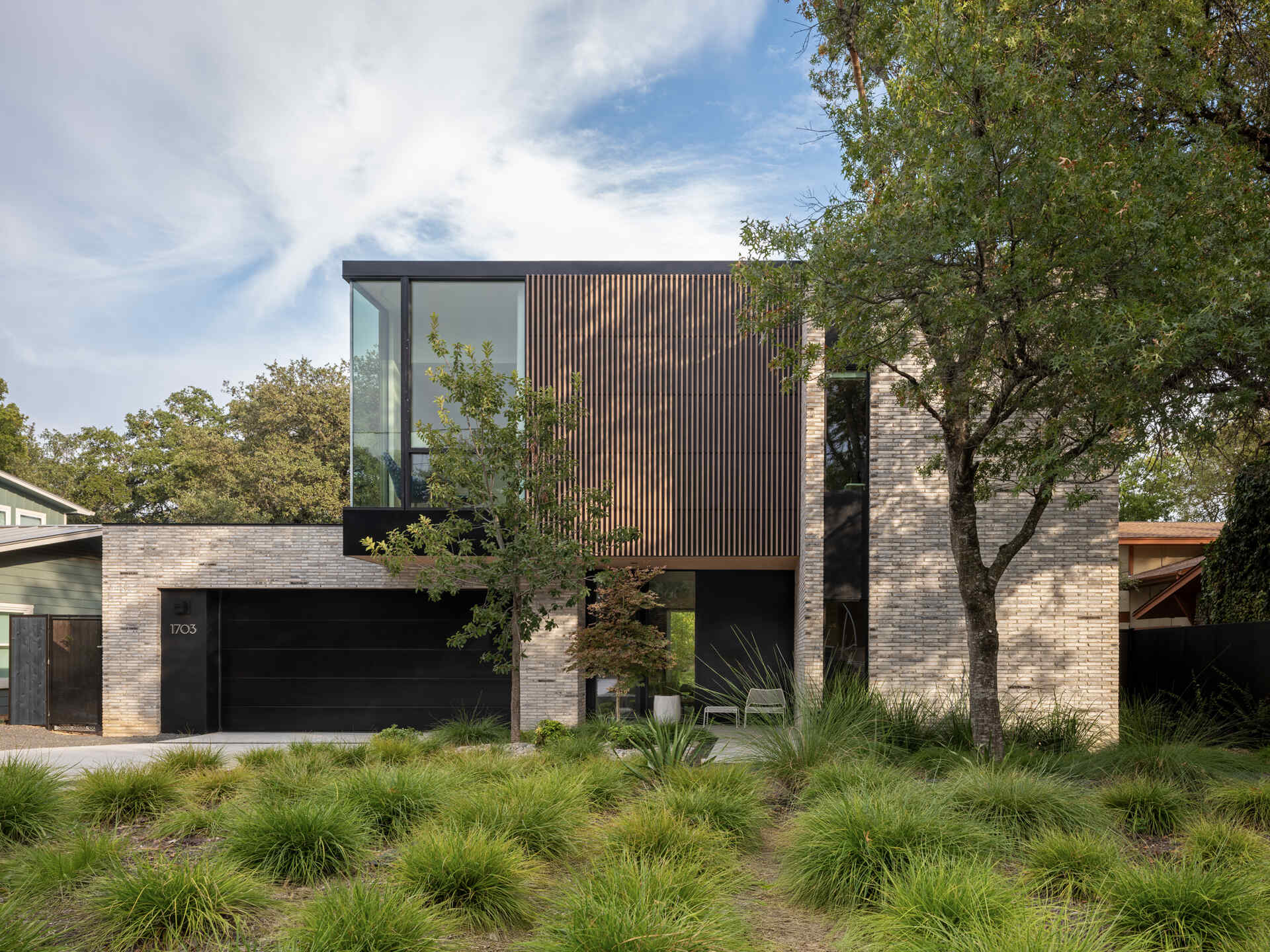 A modern infill home that breaks down its mass with brick, vertical wood battens, and carefully stepped volumes.