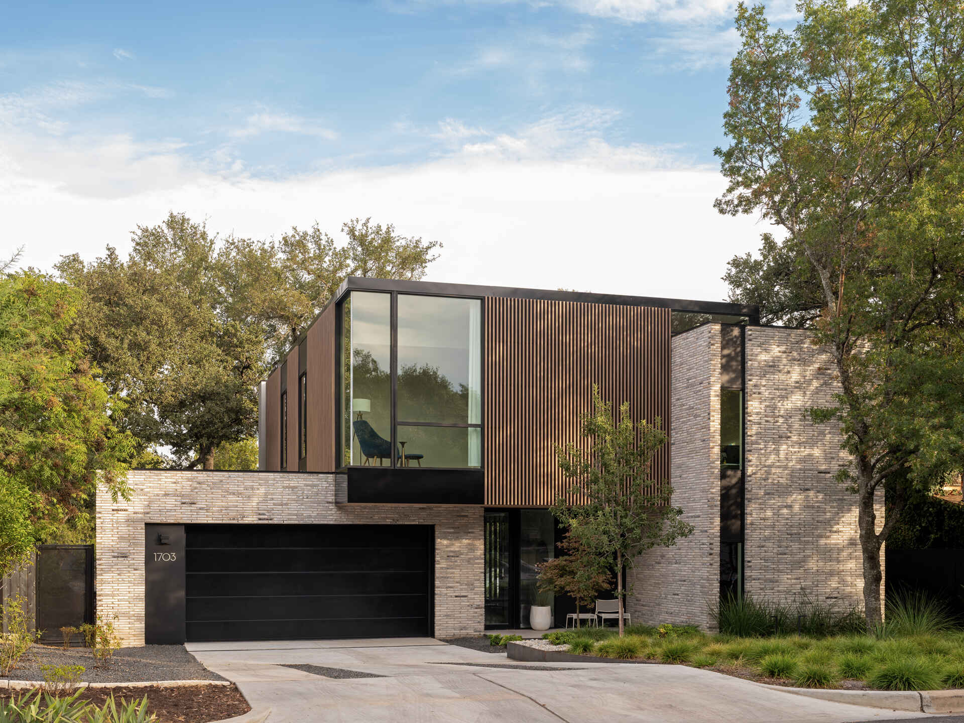 A modern infill home that breaks down its mass with brick, vertical wood battens, and carefully stepped volumes.