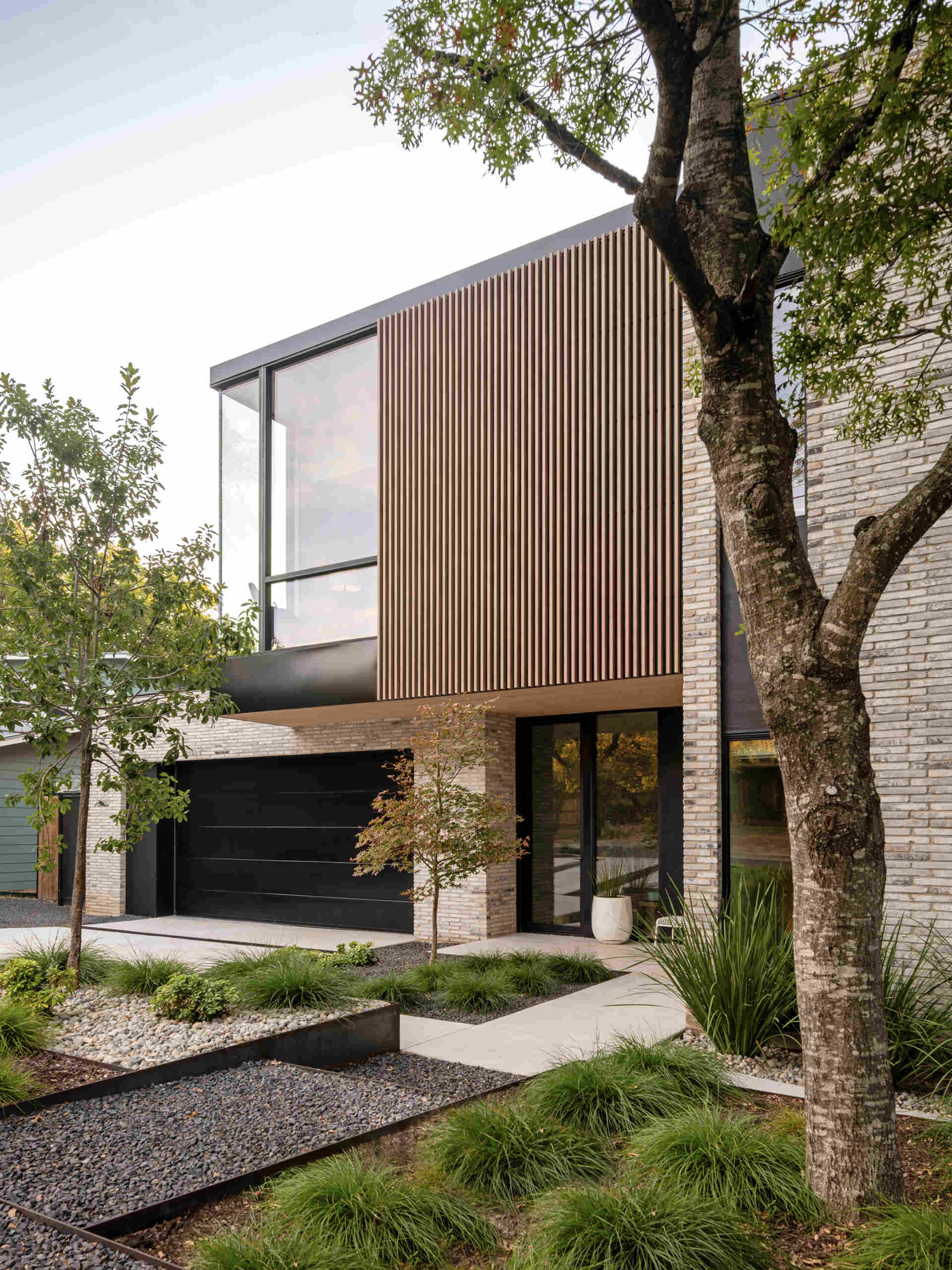 A modern infill home that breaks down its mass with brick, vertical wood battens, and carefully stepped volumes.