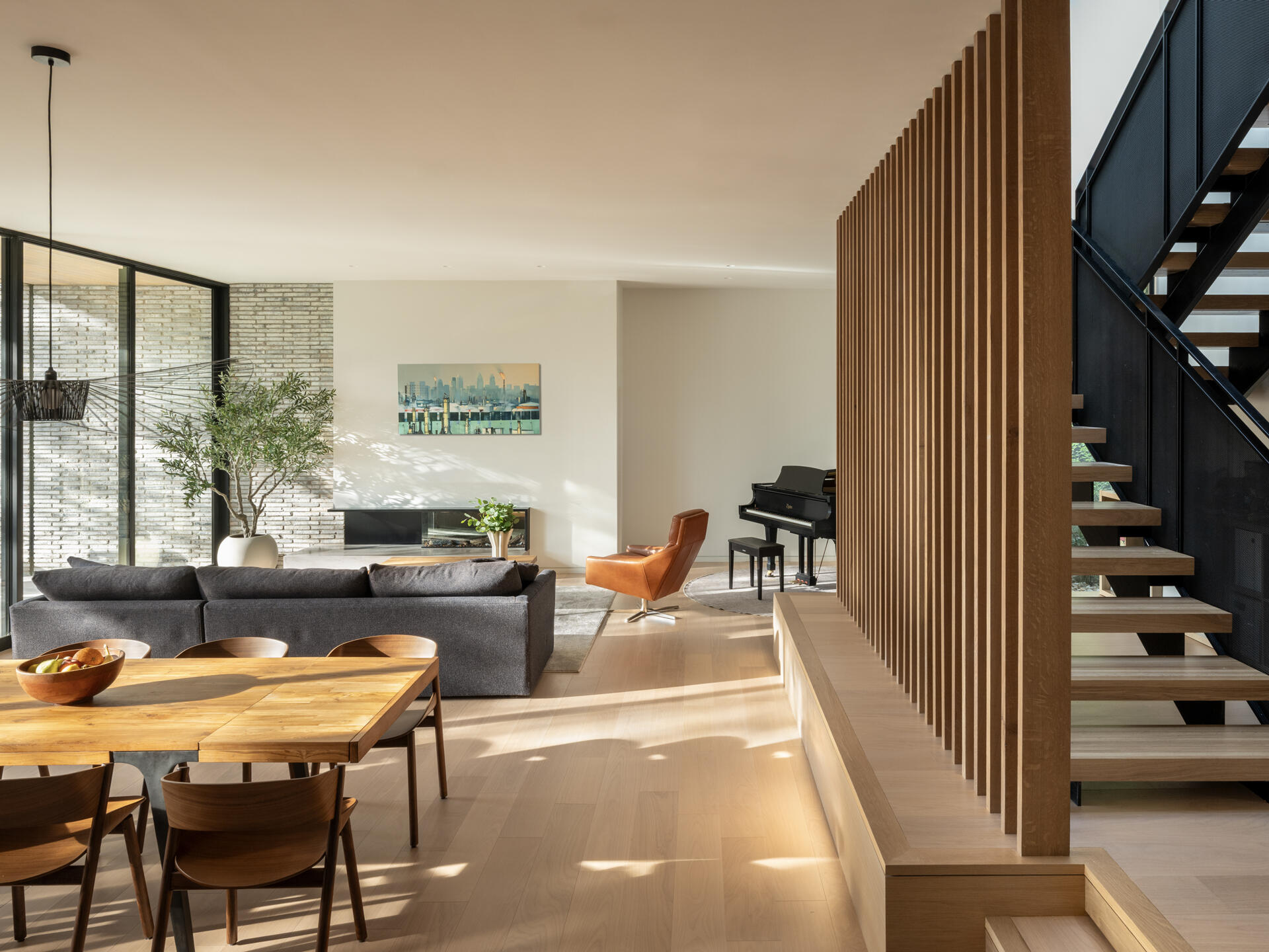 A recessed living and dining area steps down with the lot, anchored by a fireplace. Large operable glass doors connect interior and exterior, creating a layered, flowing space that feels both intimate and expansive.