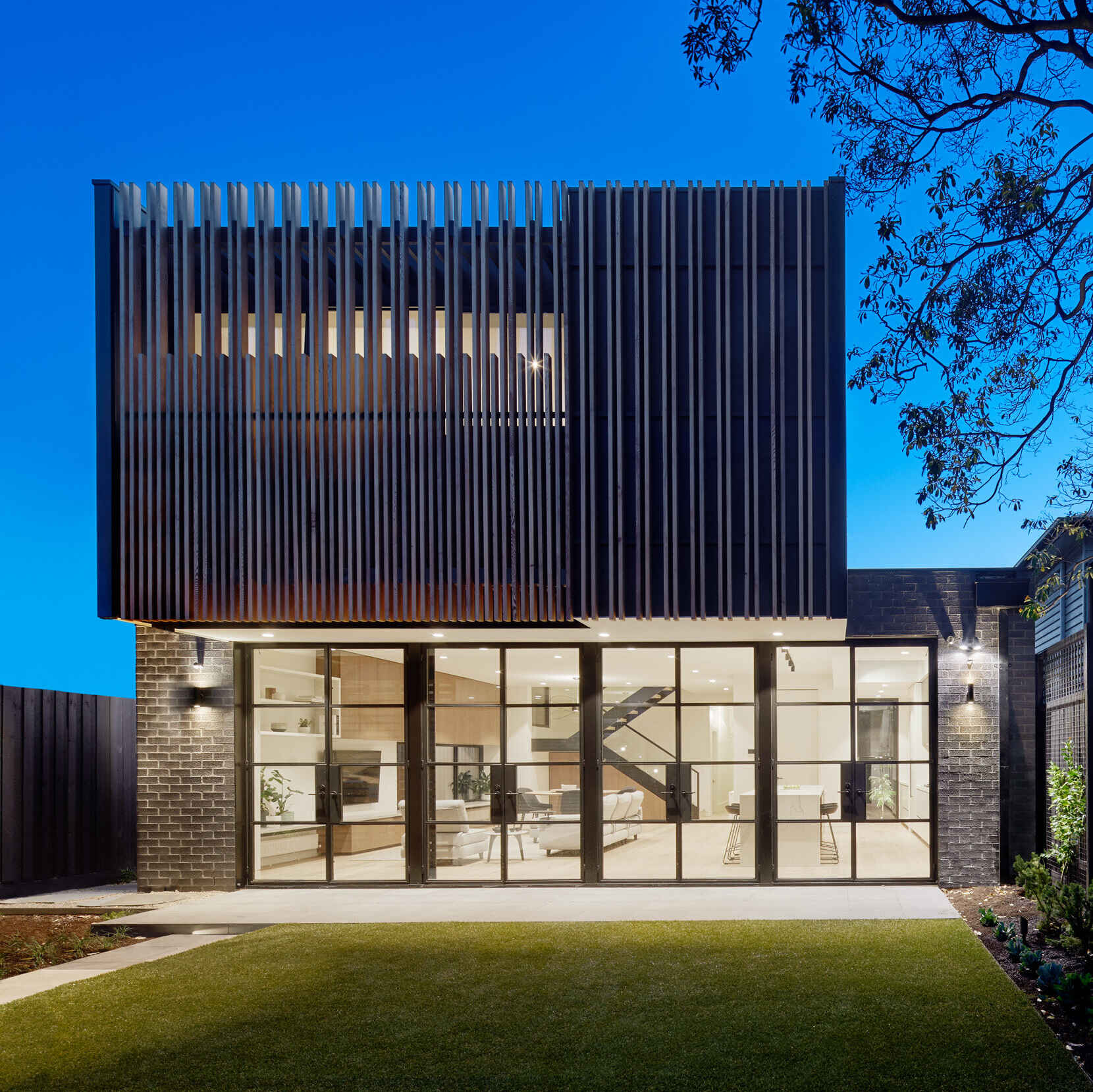Vertical timber battens wrap the upper level of this Melbourne extension, adding warmth, texture and privacy to the master bedroom while softening the modern form.