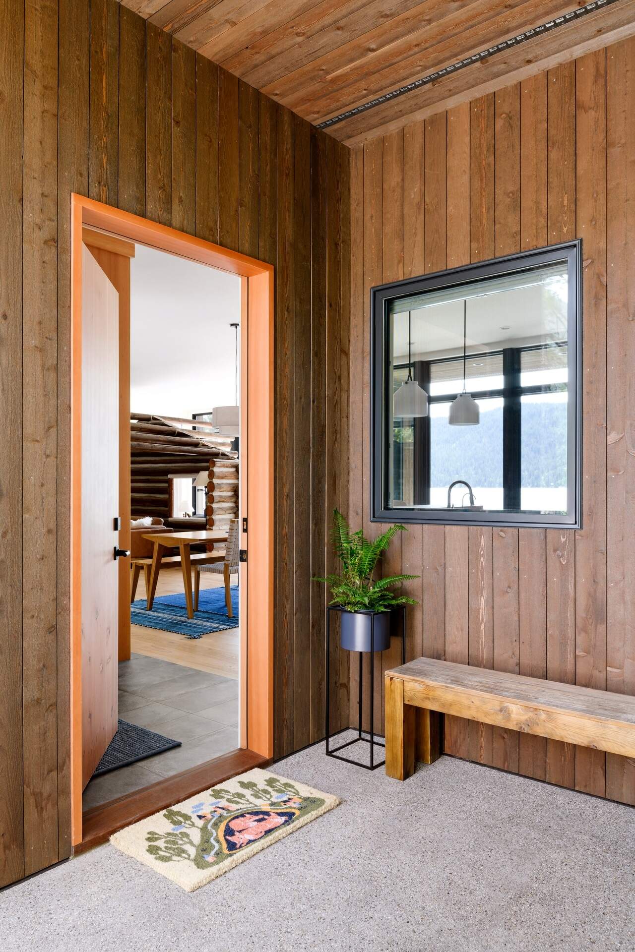 From the entry, the original cabin is visible behind glass, immediately setting the tone for the entire home.