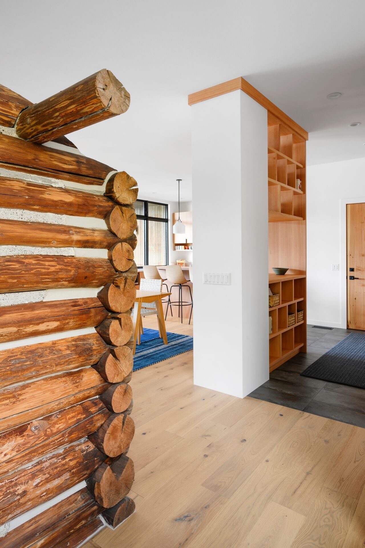 From the entry, the original cabin is visible behind glass, immediately setting the tone for the entire home.