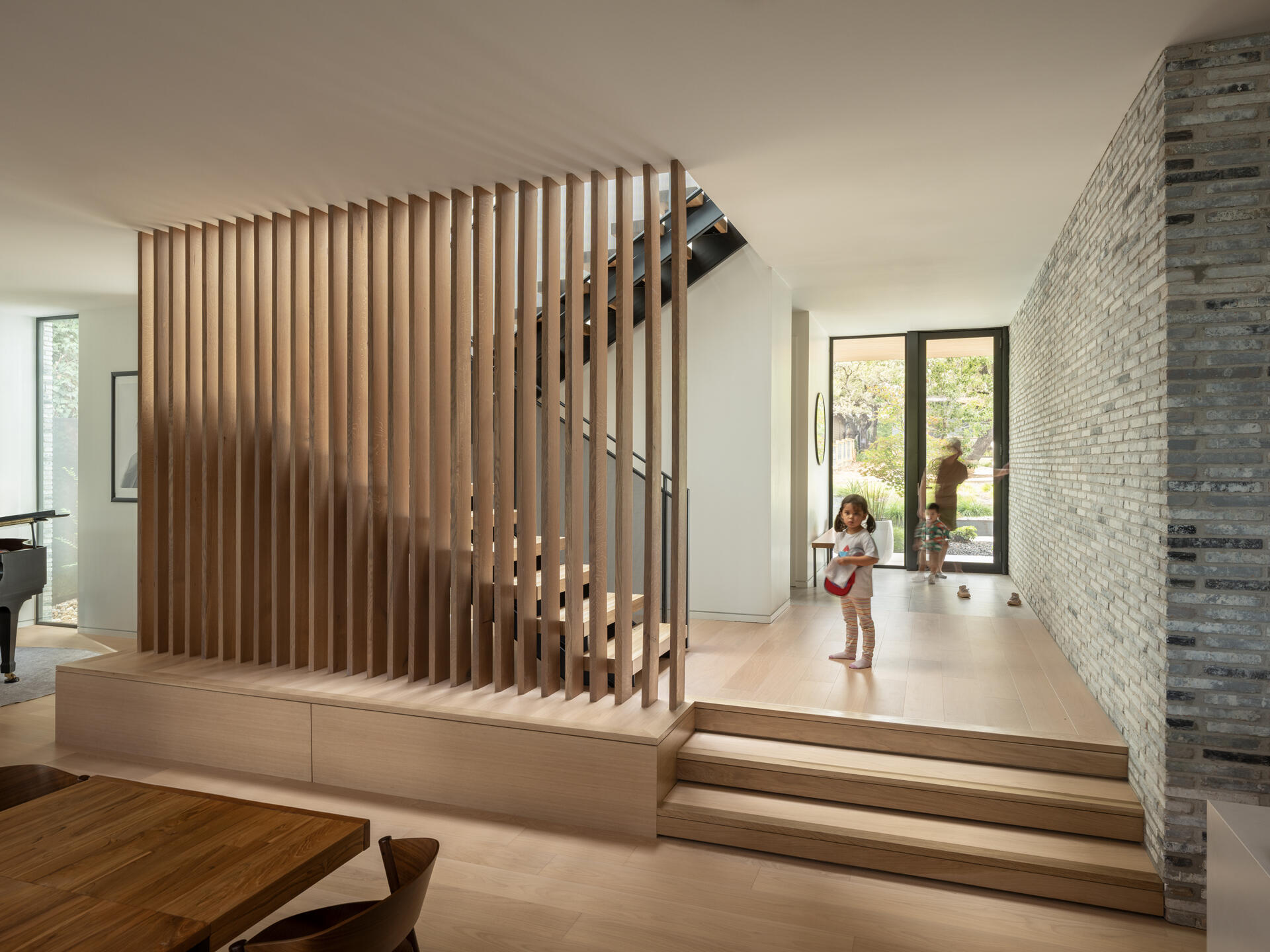 A solid, secure entryway marked by a single glazed door. Interior brick carries the exterior texture inside, setting the tone for a home that balances openness and privacy.