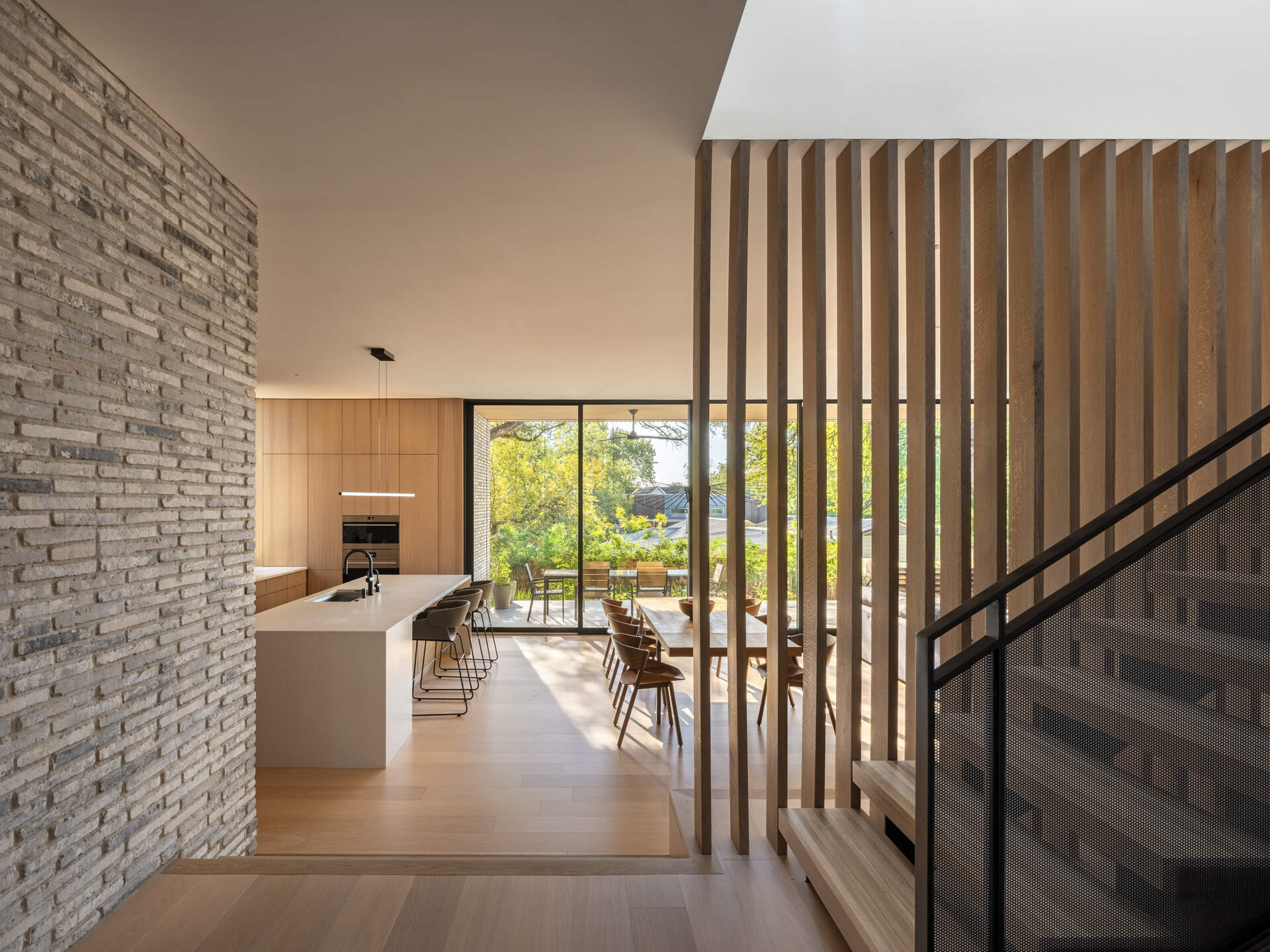 A solid, secure entryway marked by a single glazed door. Interior brick carries the exterior texture inside, setting the tone for a home that balances openness and privacy.