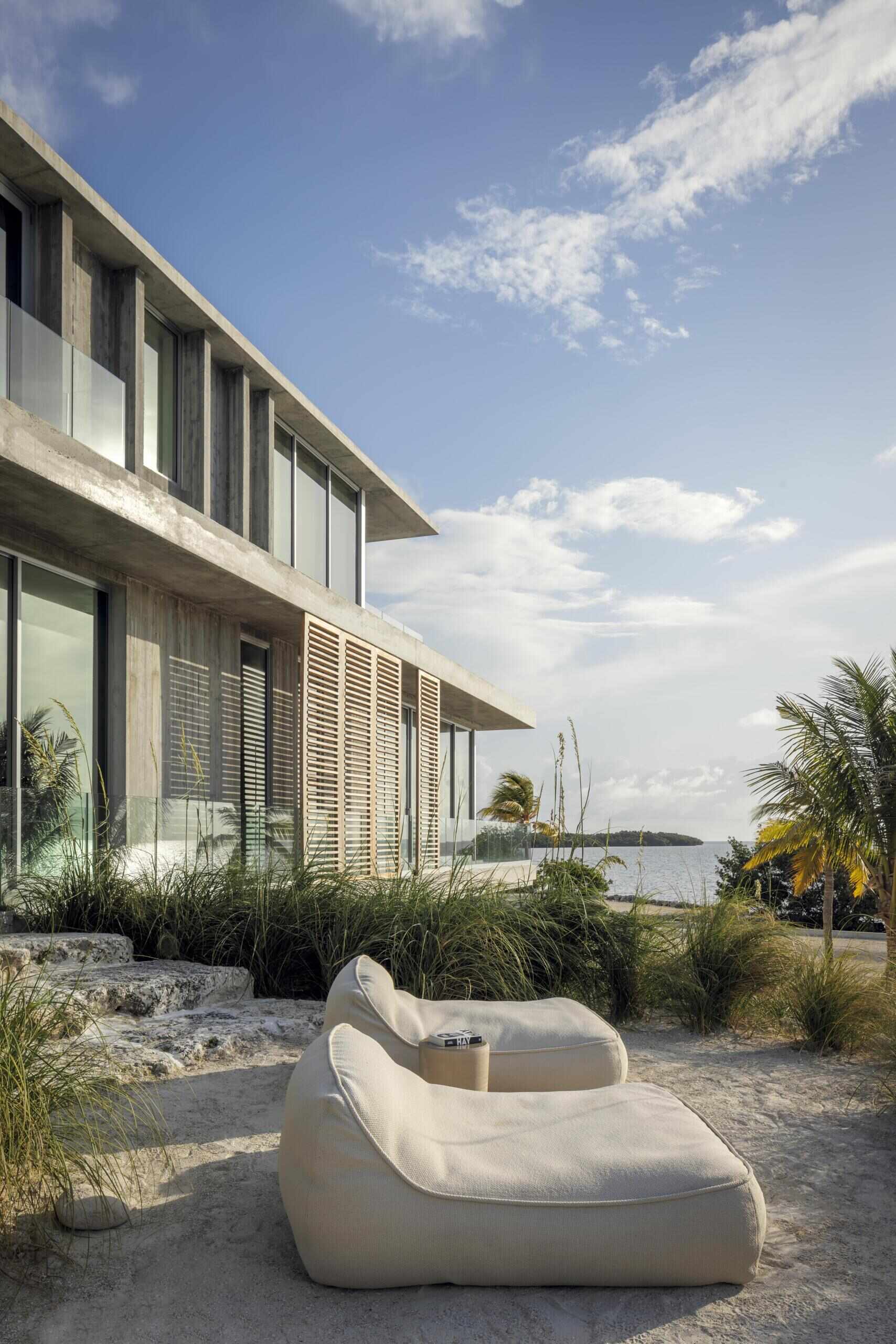 This modern home features board-formed concrete, coral rock, and wood slats that define a durable material palette built for coastal conditions.