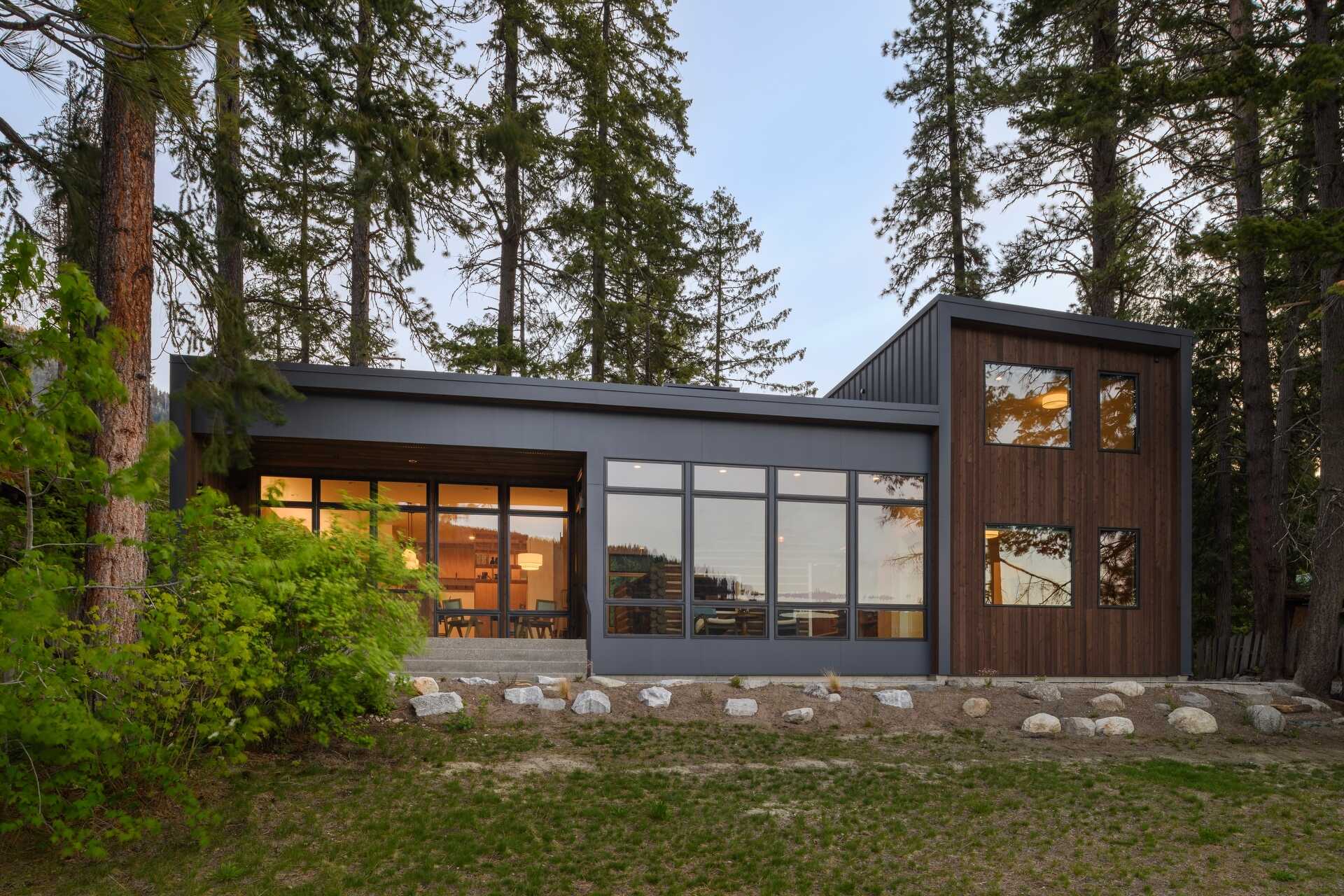 From the entry, the original cabin is visible behind glass, immediately setting the tone for the entire home.