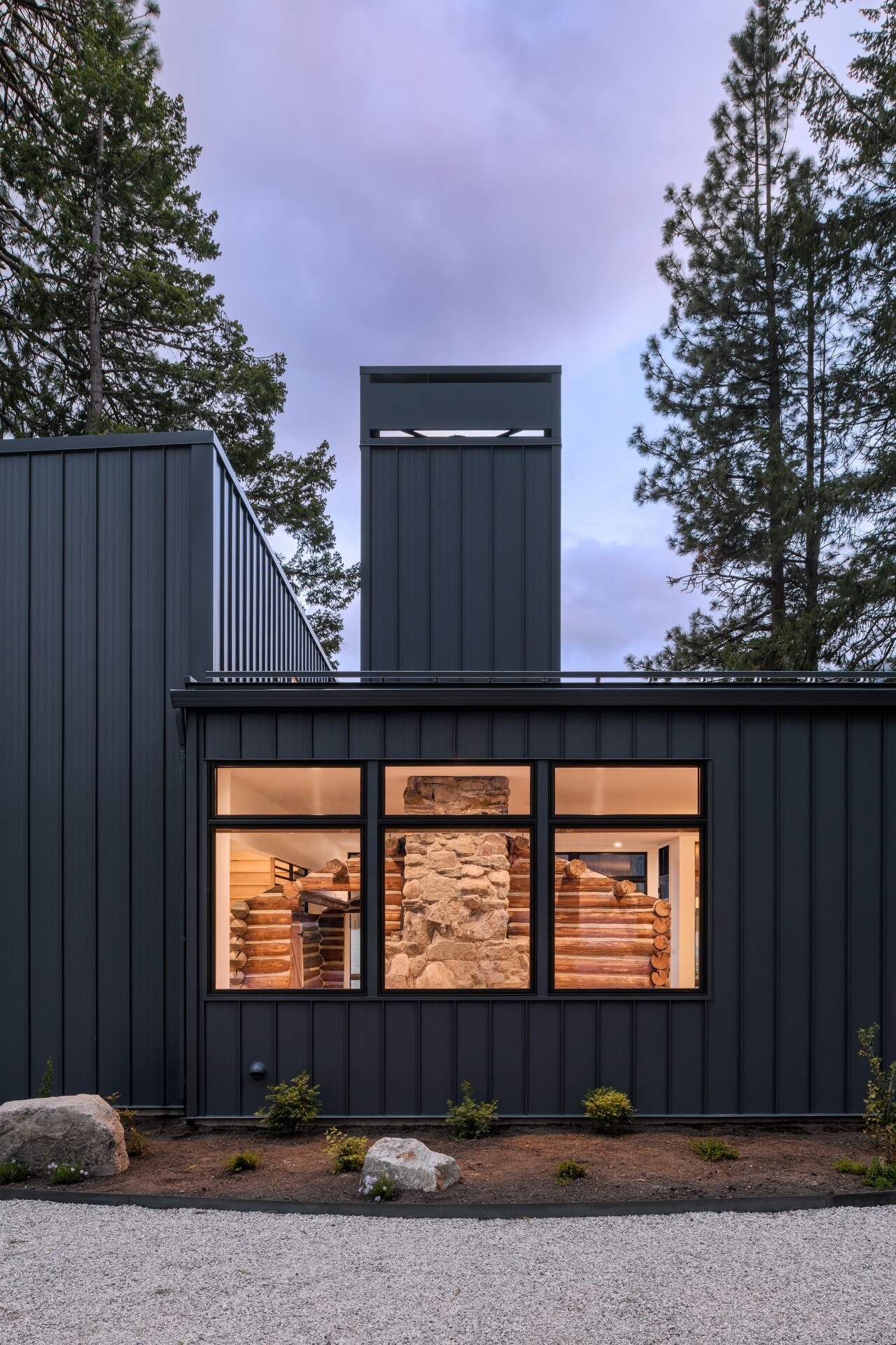 From the entry, the original cabin is visible behind glass, immediately setting the tone for the entire home.