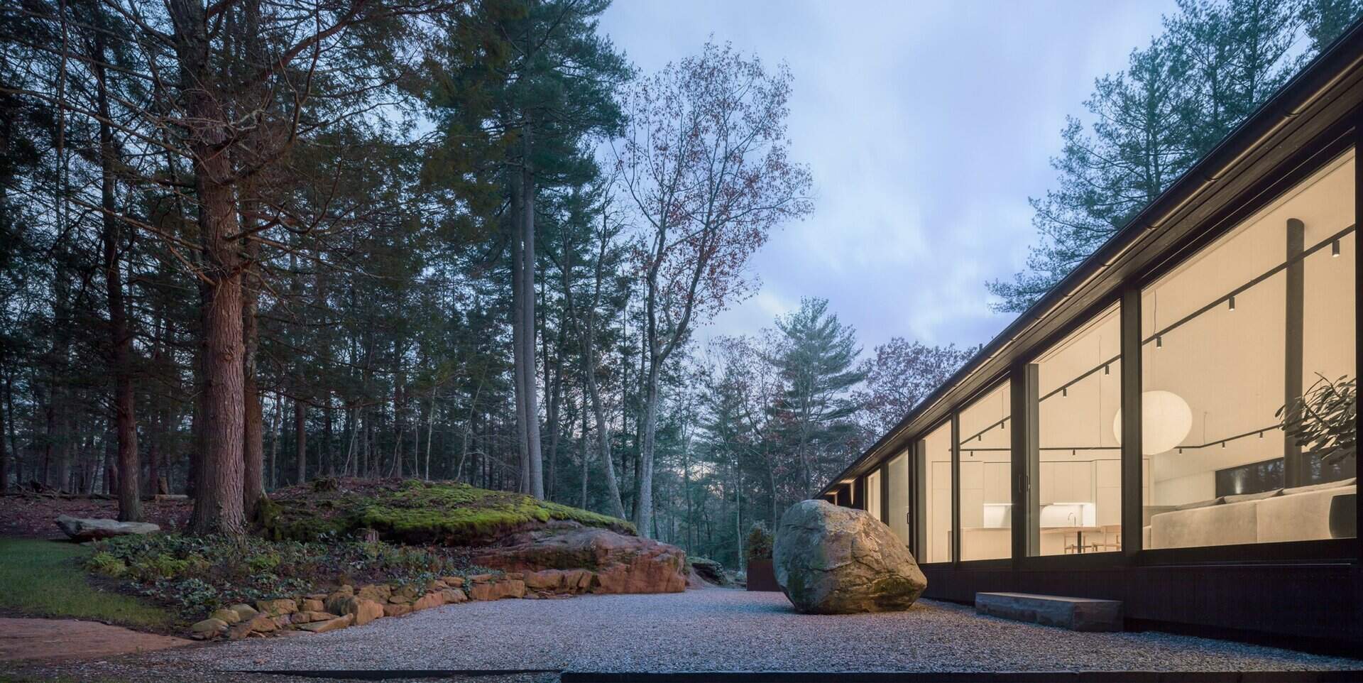 A serene entry sequence with a rock garden that connects the house to the surrounding forest. This modern Connecticut home feels rooted in the landscape from the very first step.