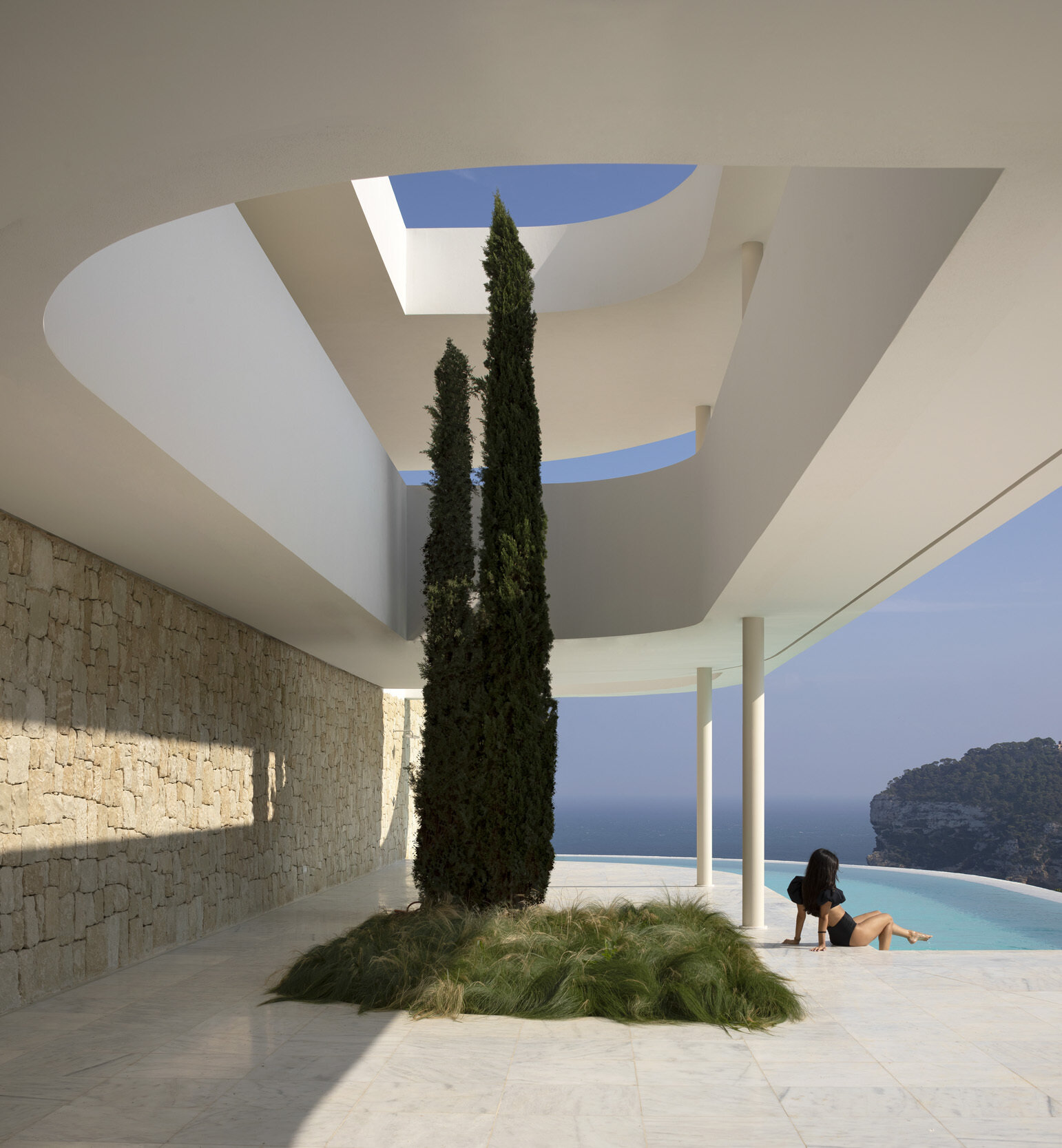 Una piscina serpenteante se funde con el horizonte mediterráneo y los cipreses corren por las terrazas, transformando el paisaje en arquitectura en esta casa española frente al mar.