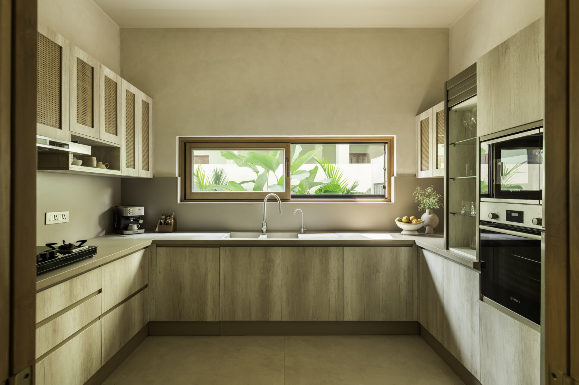 The kitchen continues the earthy monochrome palette, seamlessly connected to the dining area and courtyard to maintain the home’s calm architectural flow.