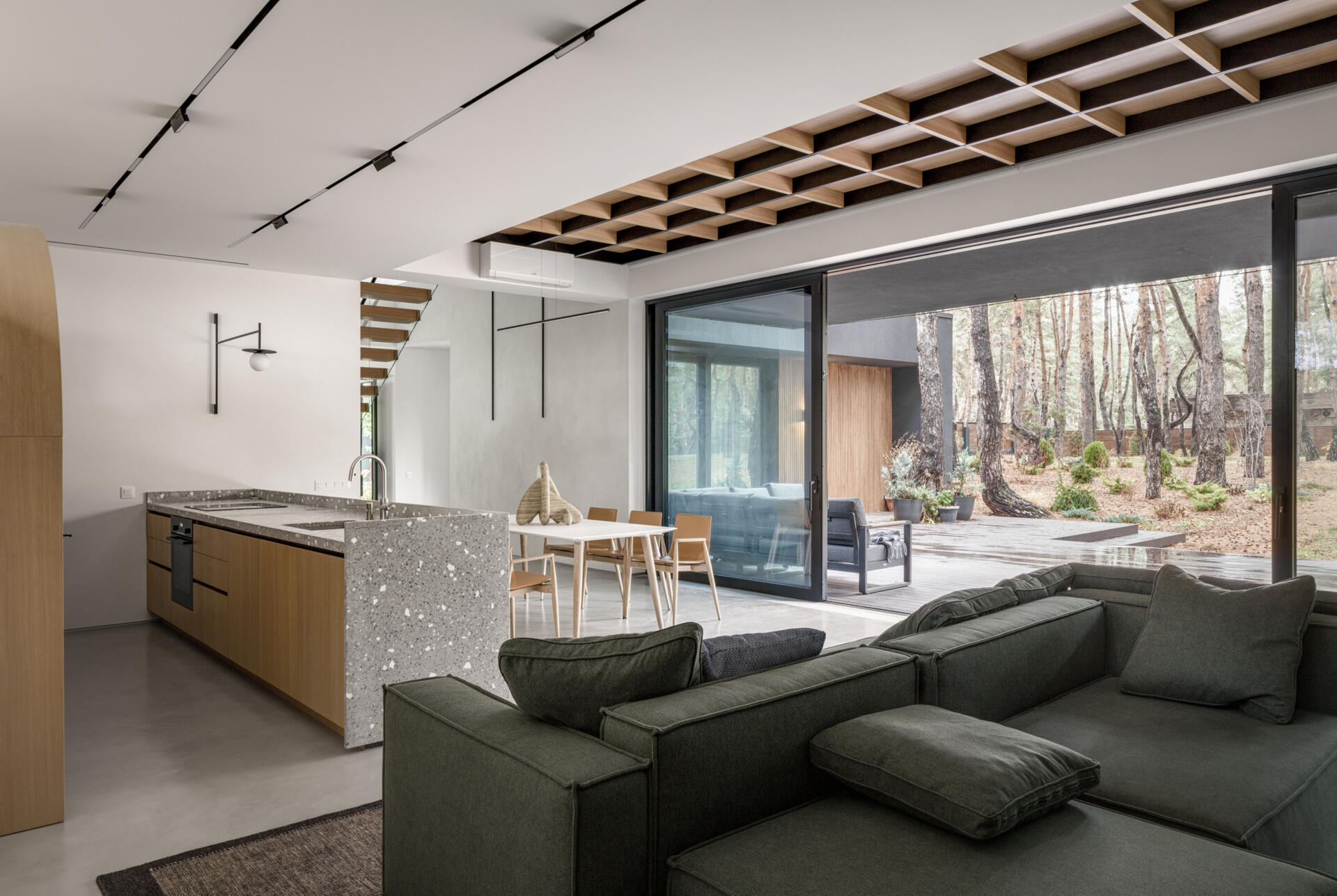 A light-filled living room with panoramic forest views, a fireplace, and large glazing that brings the outdoors into everyday life.