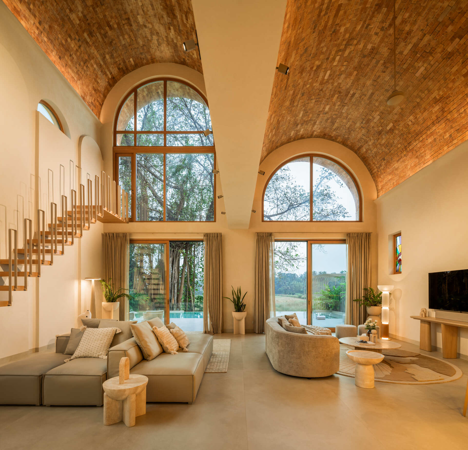 Brick vault ceilings, wooden arches and a stained glass window inspired by the Osho logo shape this serene living space. A tiny balcony offers a private lookout over the surrounding fields and sky.