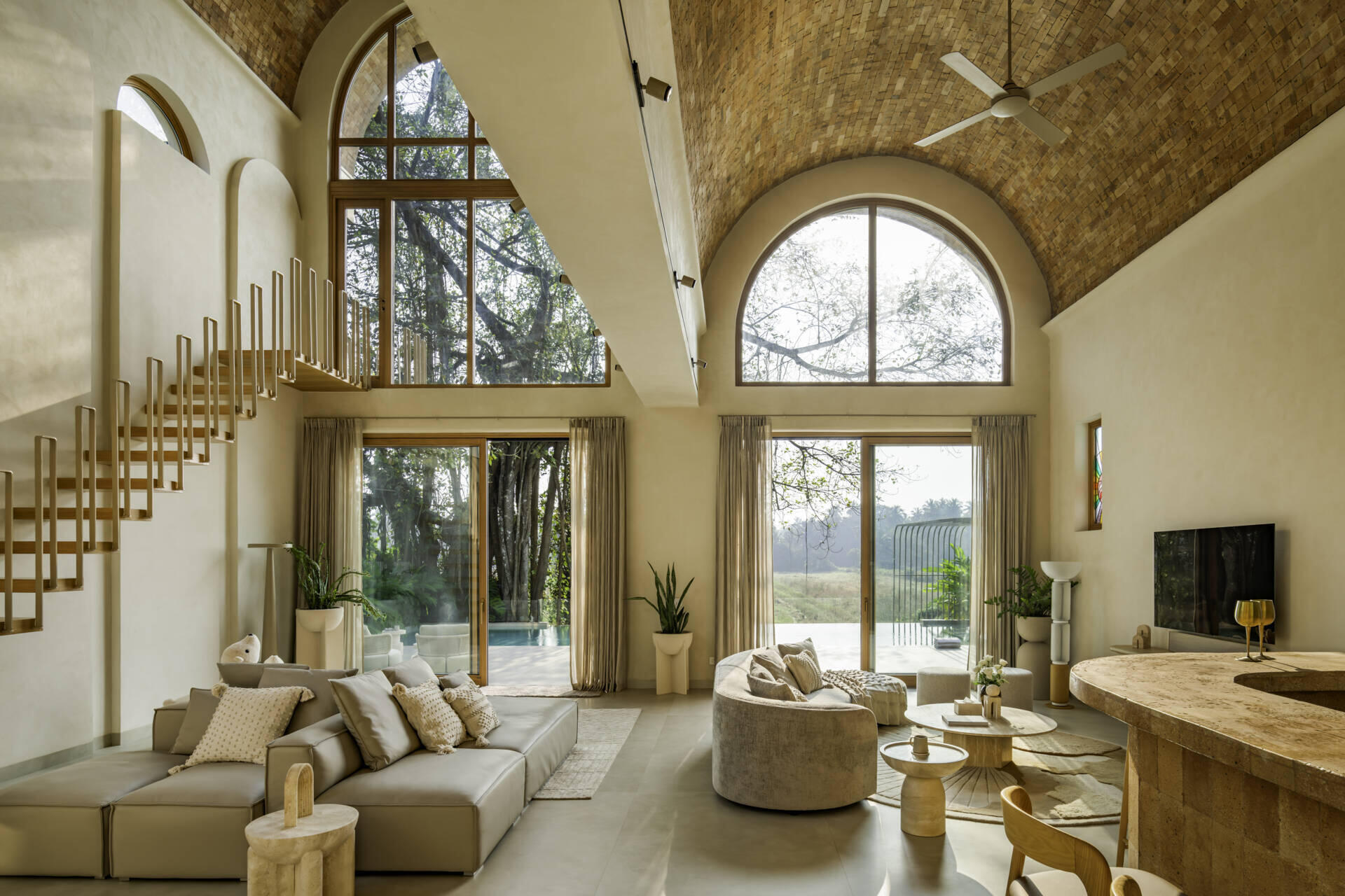 Brick vault ceilings, wooden arches and a stained glass window inspired by the Osho logo shape this serene living space. A tiny balcony offers a private lookout over the surrounding fields and sky.