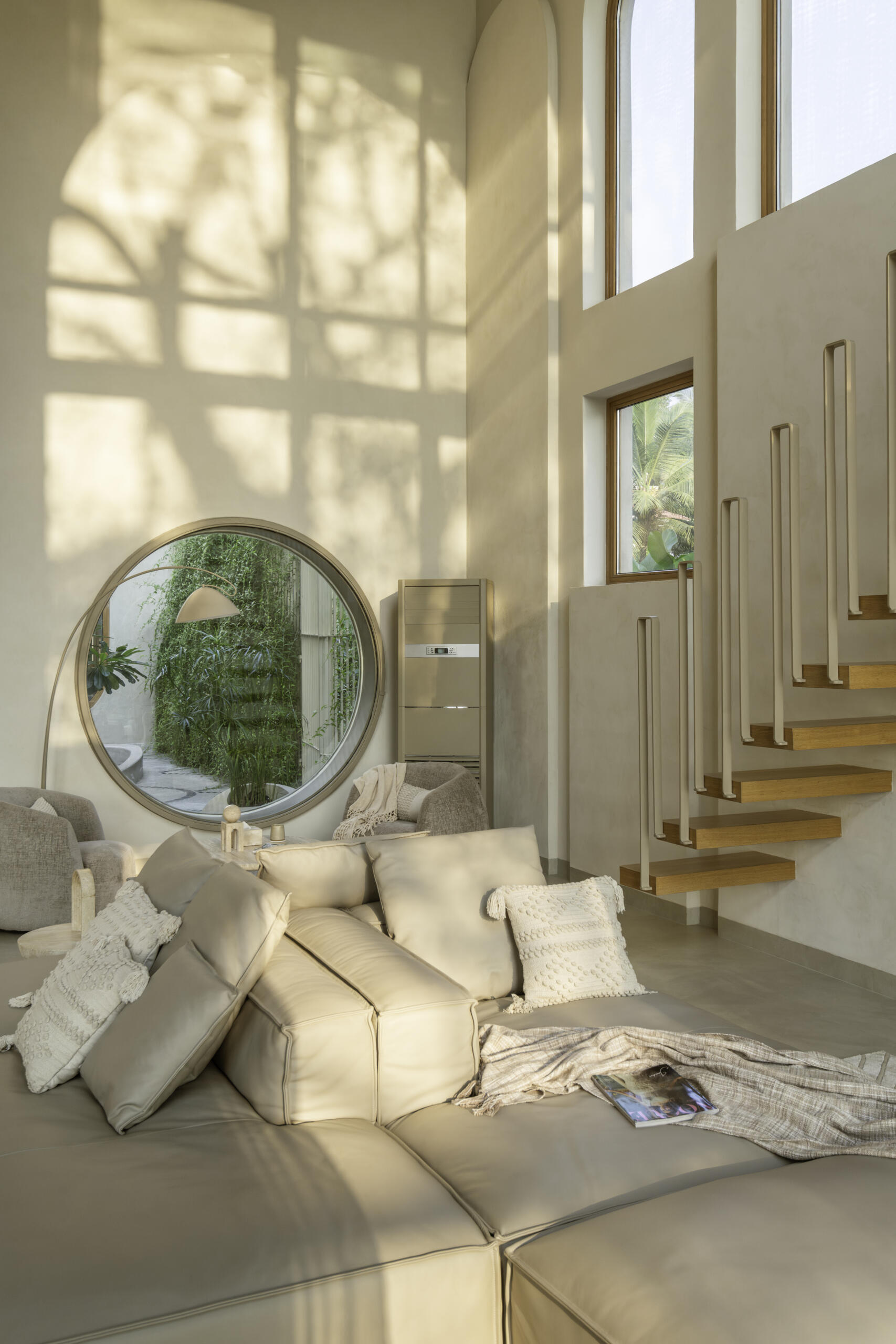 Brick vault ceilings, wooden arches and a stained glass window inspired by the Osho logo shape this serene living space. A tiny balcony offers a private lookout over the surrounding fields and sky.