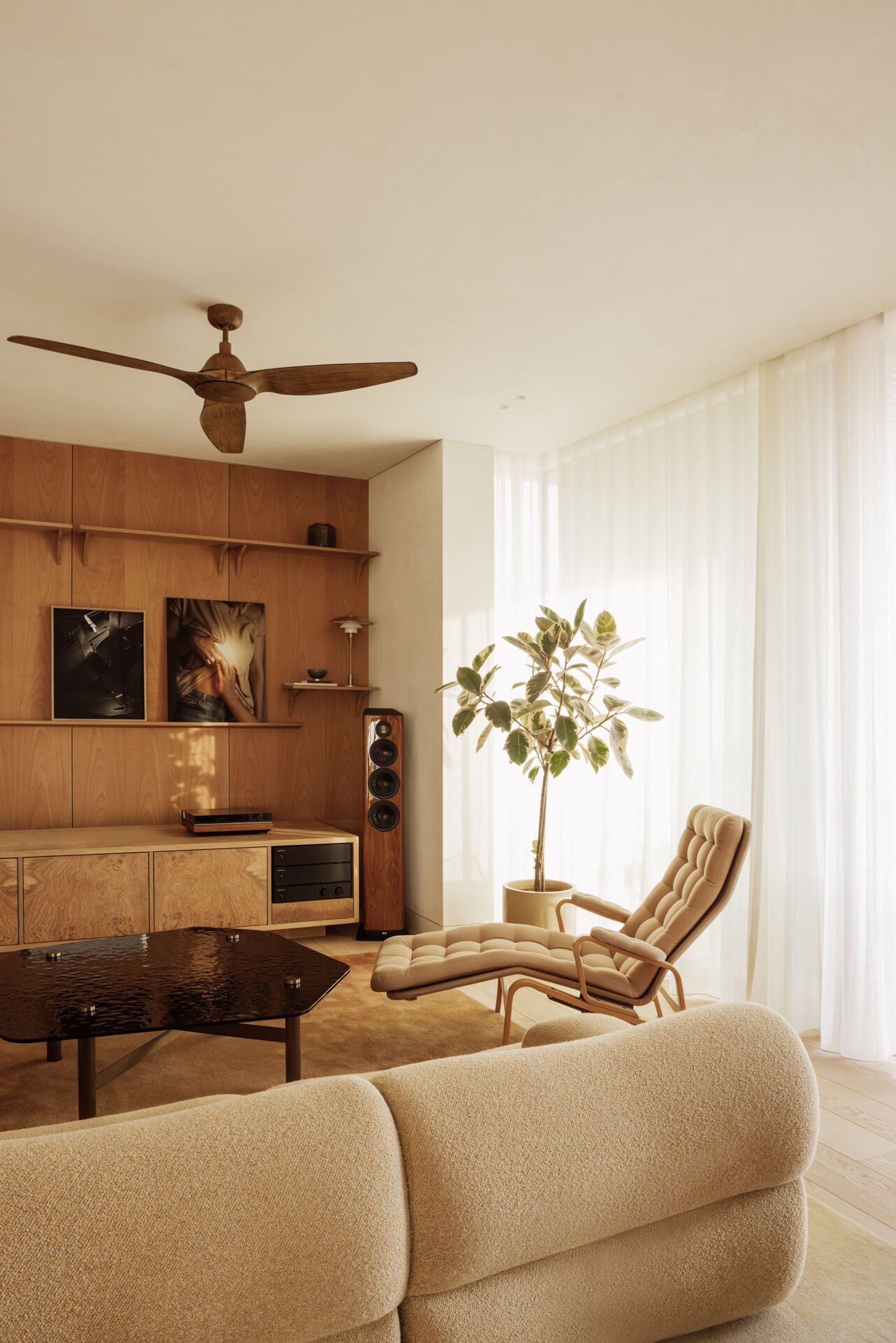 A sunlit open plan living area in Athens defined by furniture and light partitions, with large openings that frame trees and city views.