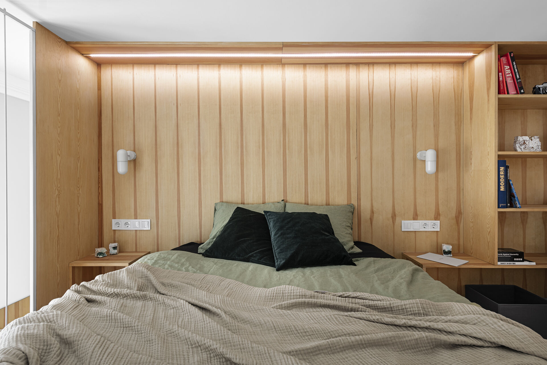 An elevated bedroom with a wood lined headboard and soft lighting, offering privacy without closing off the space below.