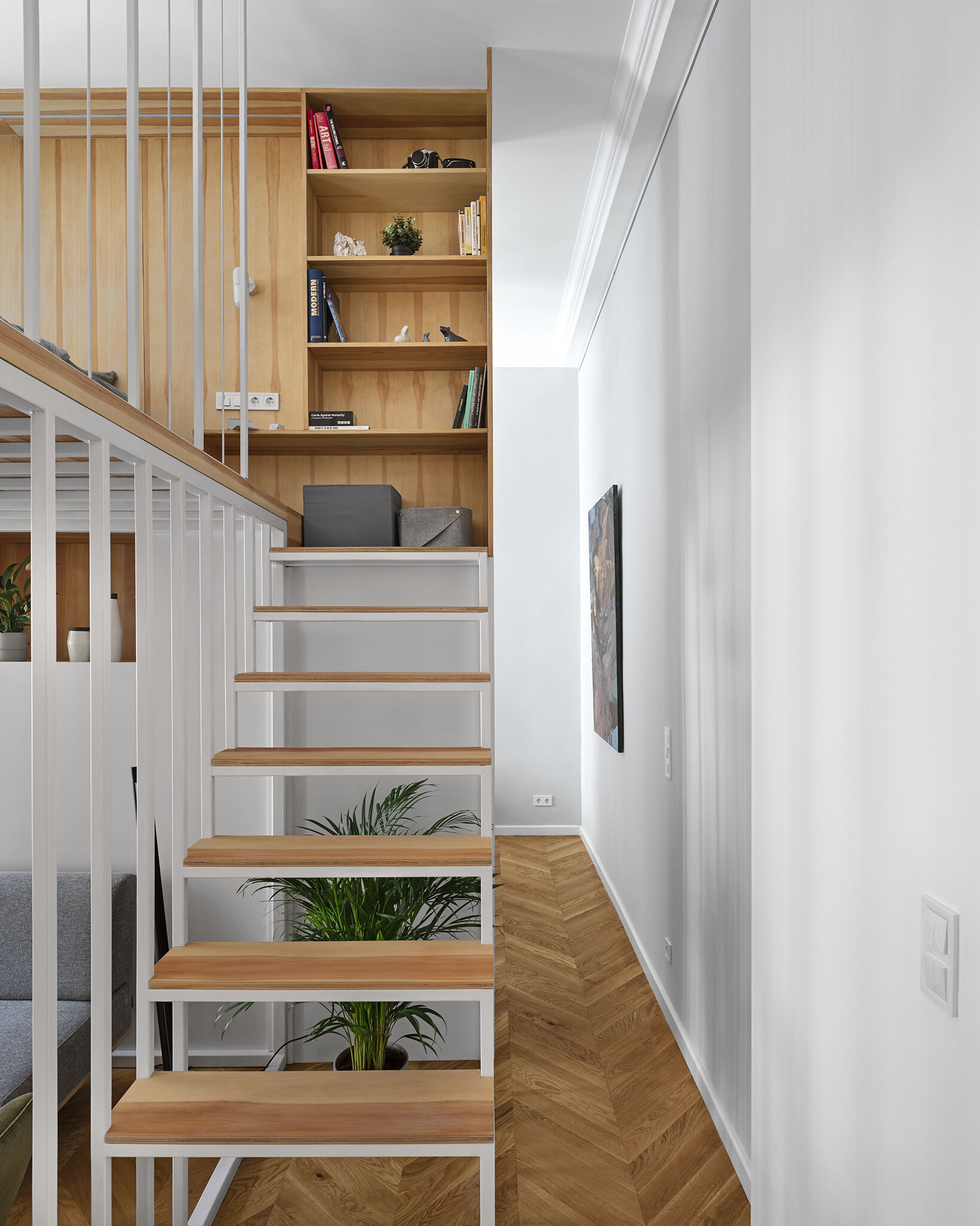 A sculptural staircase leading to a mezzanine, featuring a built in bookcase that blends storage with architectural flow.