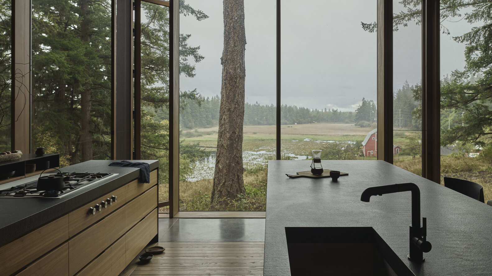 On the opposite side of the living room sits a kitchen made for feeding a crowd. Two generous islands provide ample counter space, making it easy for several people to cook at once. Along one wall, cabinetry adds additional storage and houses the ovens, keeping the layout streamlined and functional.