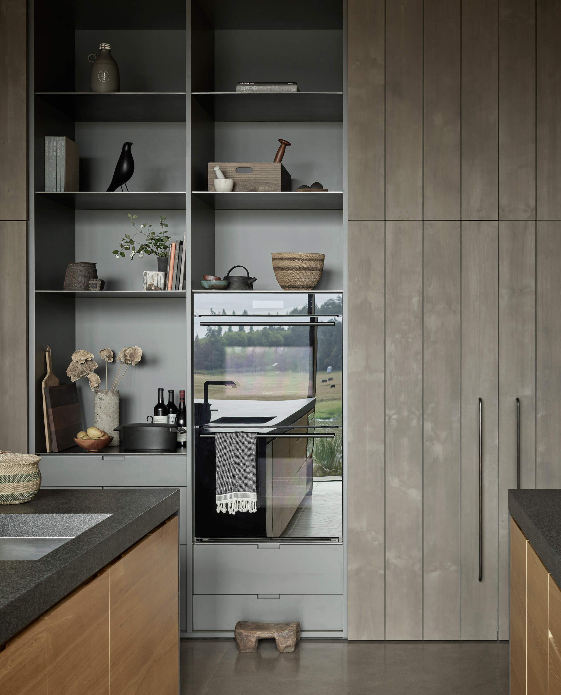 On the opposite side of the living room sits a kitchen made for feeding a crowd. Two generous islands provide ample counter space, making it easy for several people to cook at once. Along one wall, cabinetry adds additional storage and houses the ovens, keeping the layout streamlined and functional.