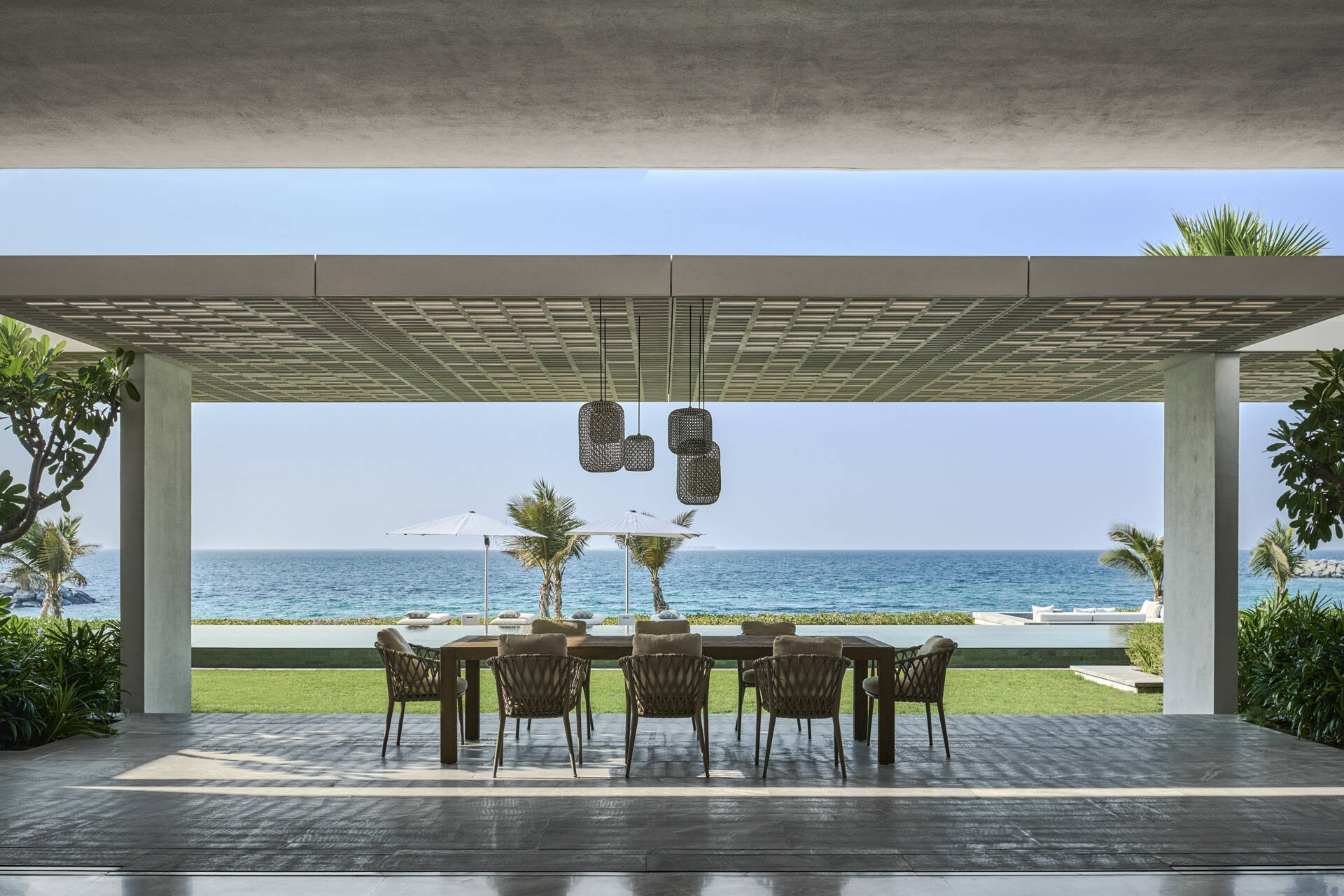 Shaded terraces extend the interior outdoors with generous eaves that reduce glare and heat. Outdoor dining sits within a planted garden setting, connected through wide glazed openings.