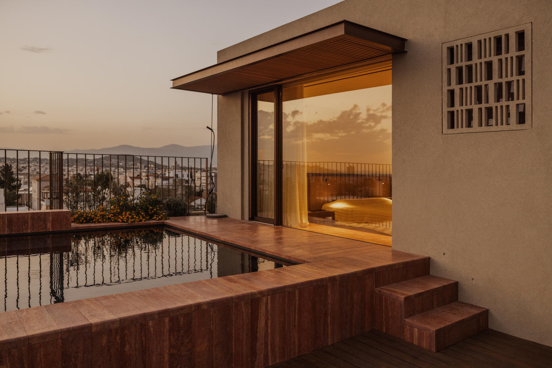 A south facing roof terrace in Papagou featuring a swimming pool, deck and half size basketball court surrounded by greenery.
