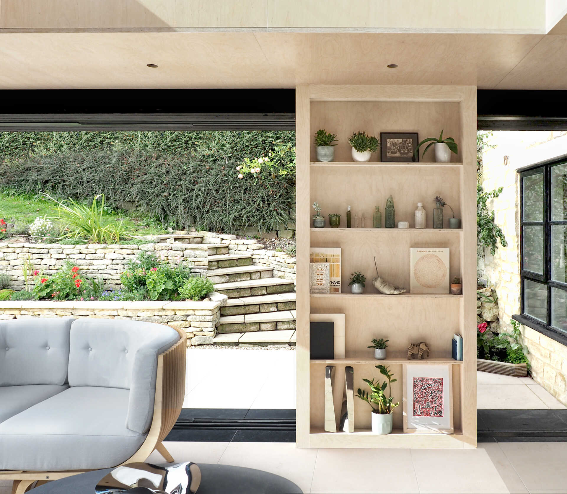 Un interior de madera contrachapada de abedul brillante, muebles modulares y terrazas ajardinadas permiten que la sala de lectura fluya fácilmente desde el interior hasta el jardín.